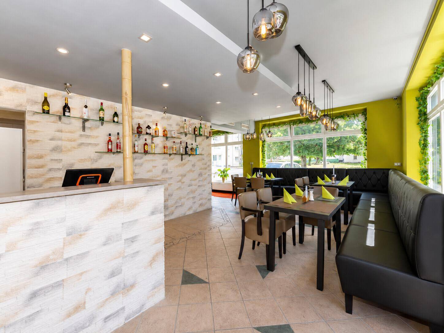 Moderner Gastraum mit Bar, grünen Wänden und bequemen Sitzgelegenheiten, ideal für gesellige Runden.