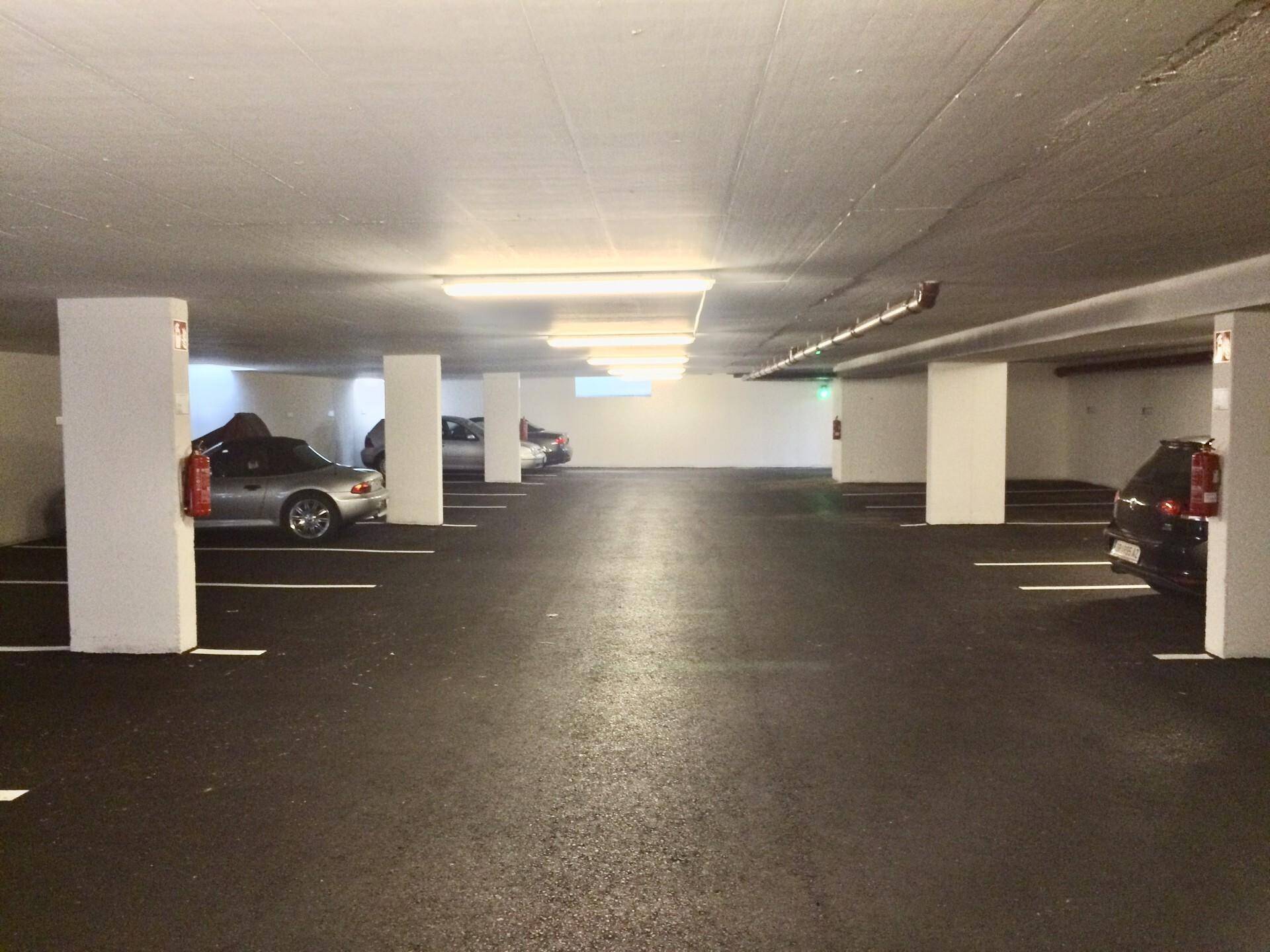 Geräumige und gut beleuchtete Tiefgarage mit vielen freien Stellplätzen und Säulen.