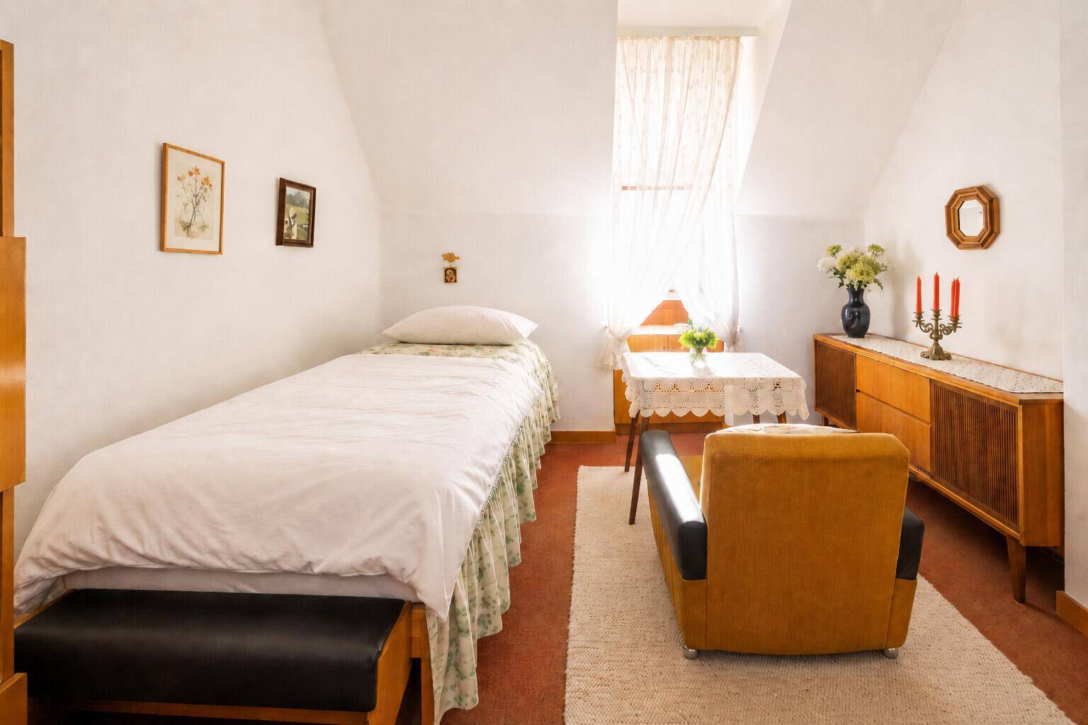 Helles Schlafzimmer im Dachgeschoss mit Einzelbett, Holzmöbeln und Teppich.