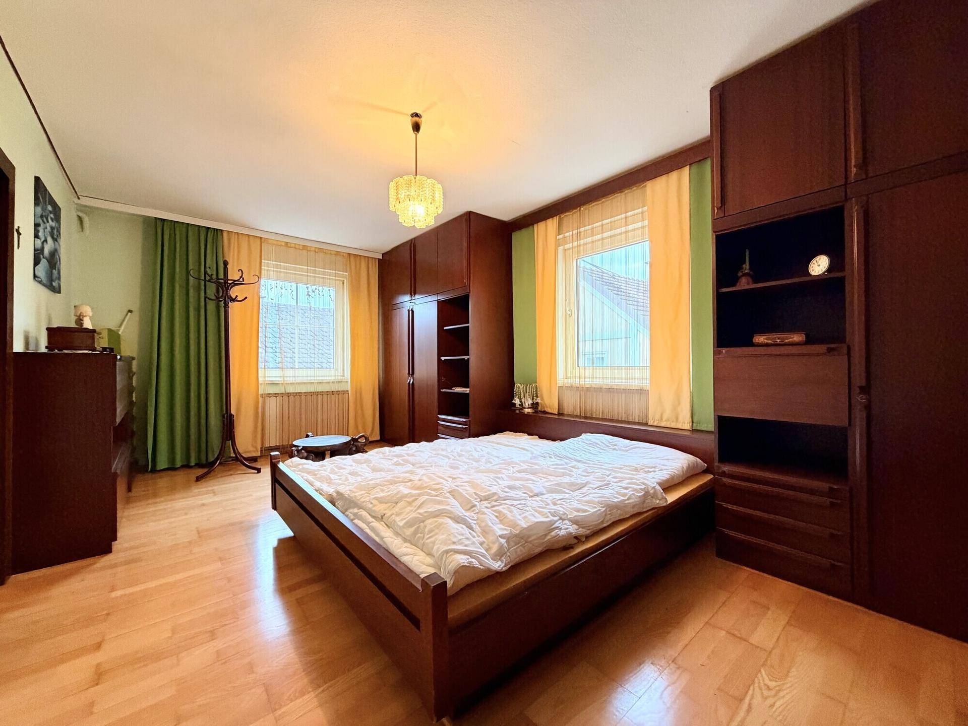Geräumiges Schlafzimmer mit Doppelbett, Einbauschränken und Holzboden.