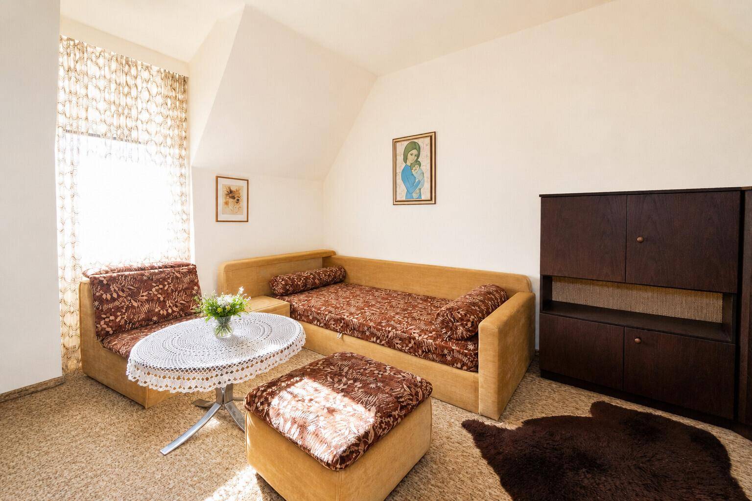 Gemütliches Dachzimmer mit Schlafcouch, Teppichboden und schrägen Wänden.