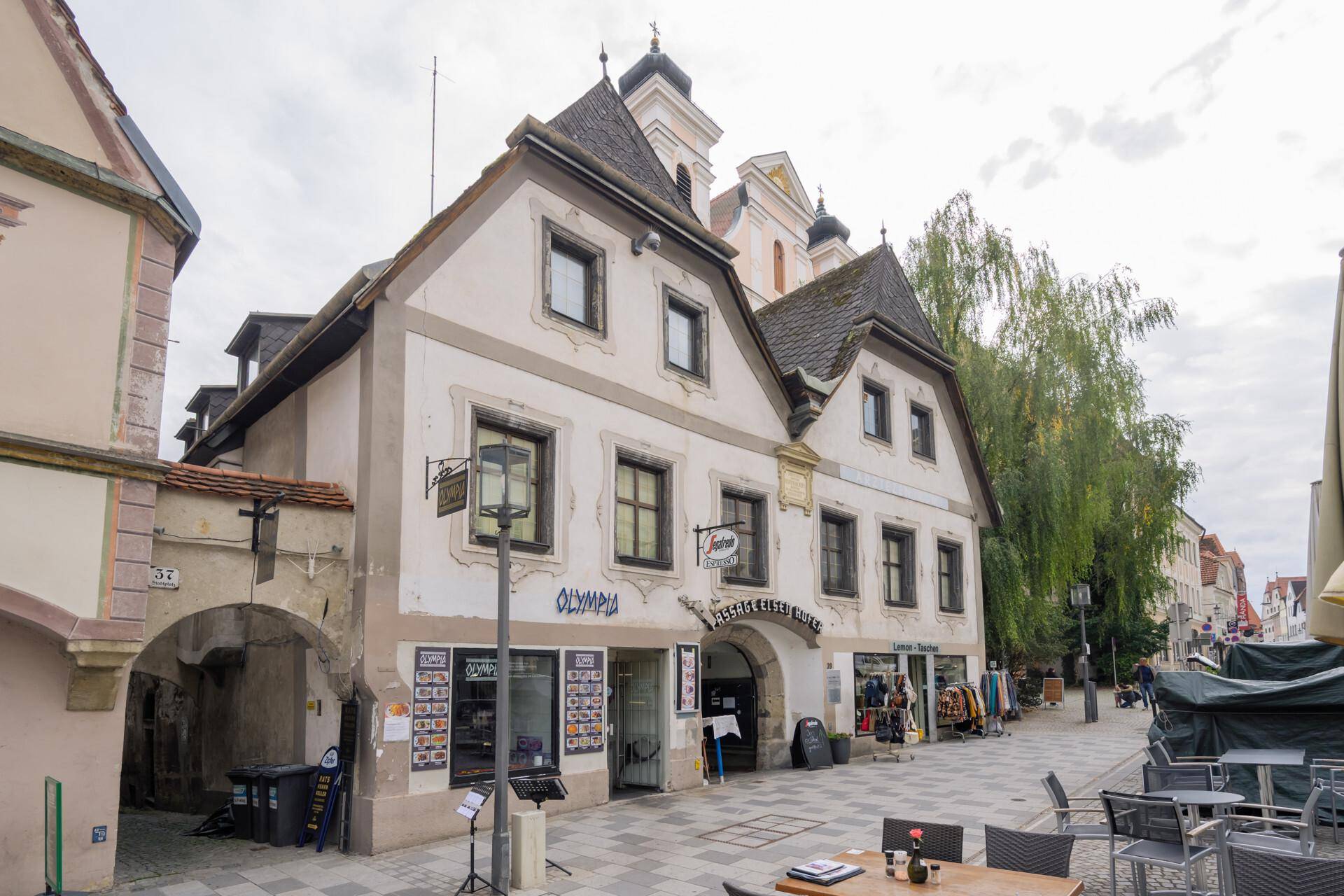 Historisches Gebäude mit Geschäften und traditioneller Architektur in der Stadt, von der Seite gesehen.