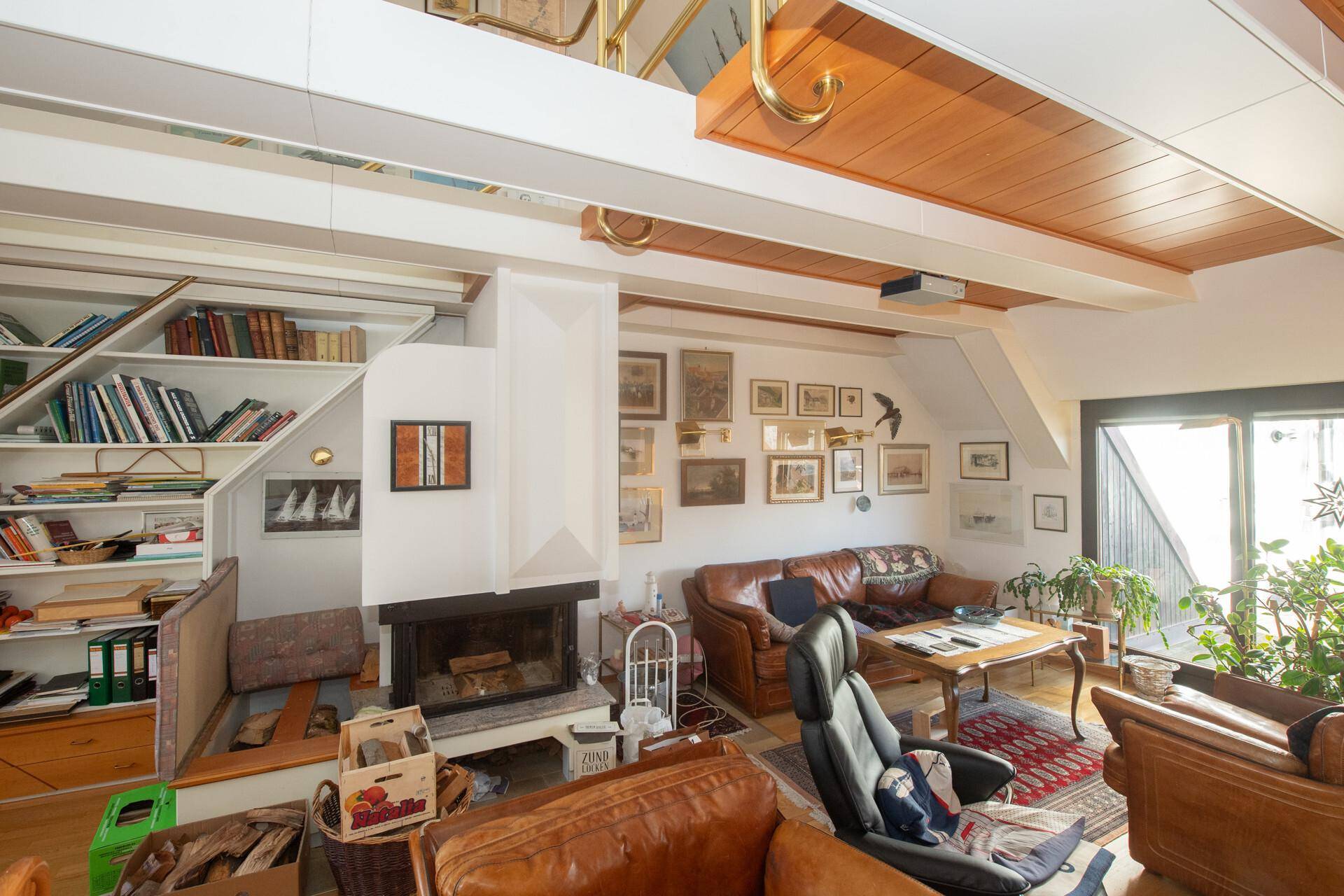 Geräumiger Wohnbereich mit Kamin, Ledersofas und einer offenen Galerie im Dachgeschoss.