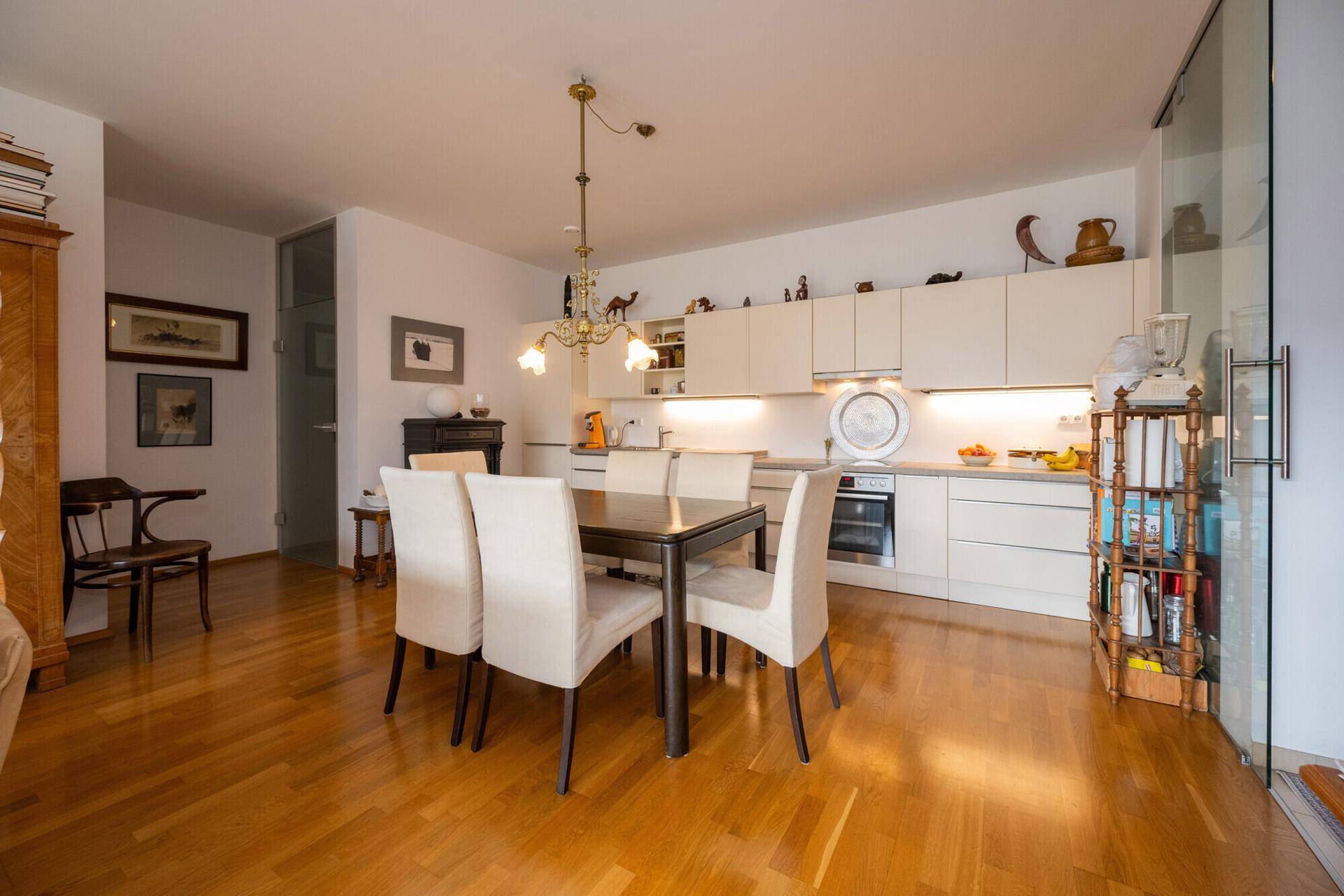 Heller offener Wohn- und Essbereich mit moderner Einbauküche und Holzboden.