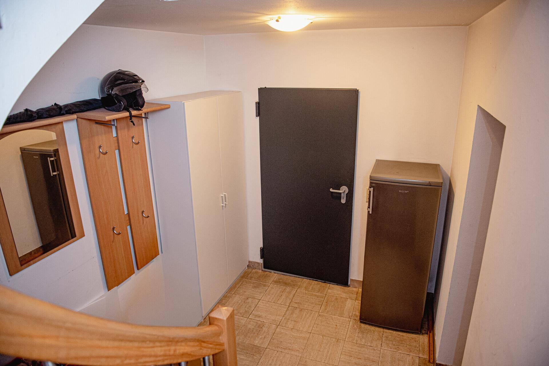 Flur oder Treppenabsatz mit Garderobe, einer dunklen Tür und einem Kühlschrank, der zusätzlichen Stauraum bietet.