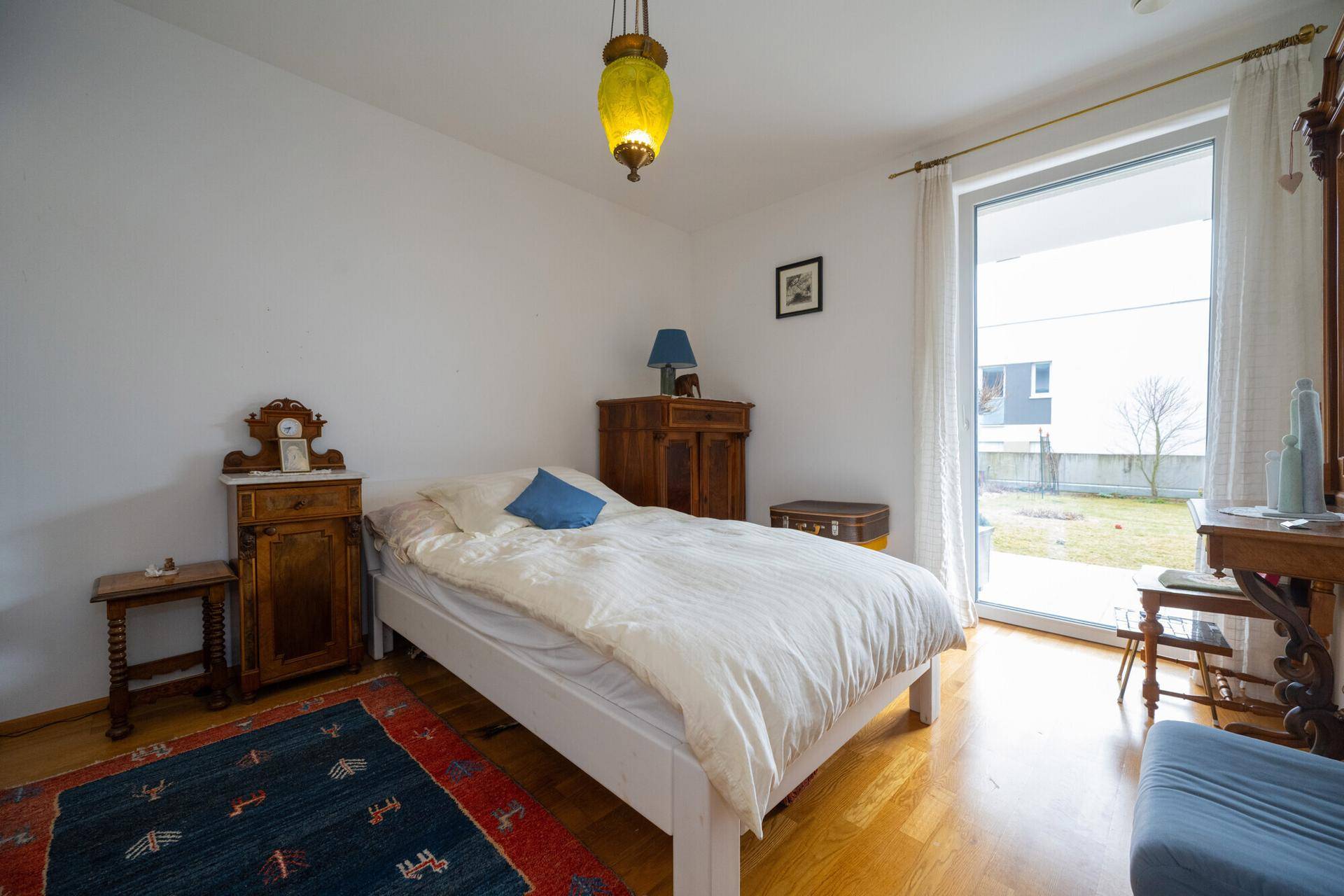 Schlafzimmer mit Holzboden, Zugang zum Garten und traditionellen Holzmöbeln.