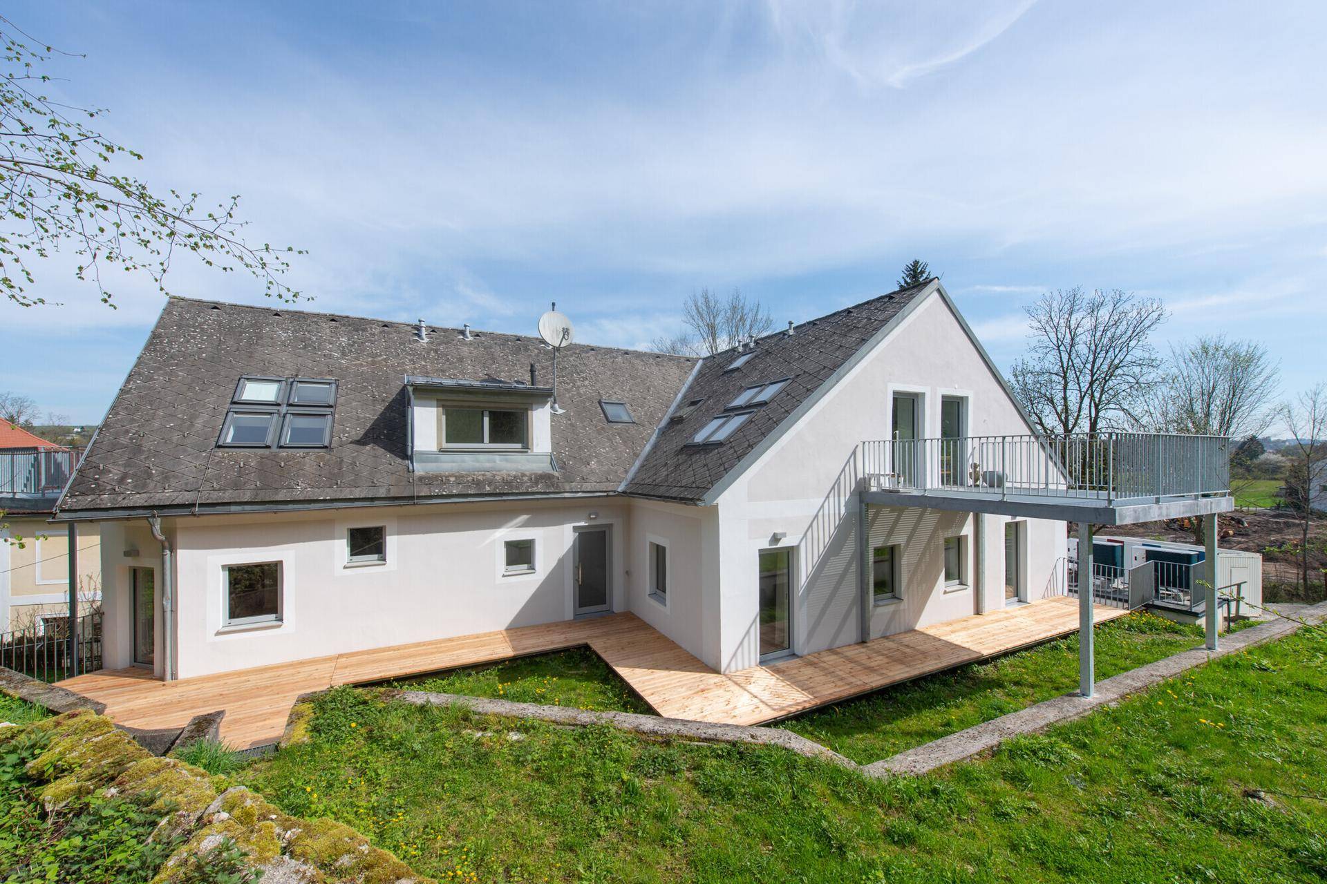 Modernes Einfamilienhaus mit mehreren Balkonen und Terrassen in ländlicher Umgebung.