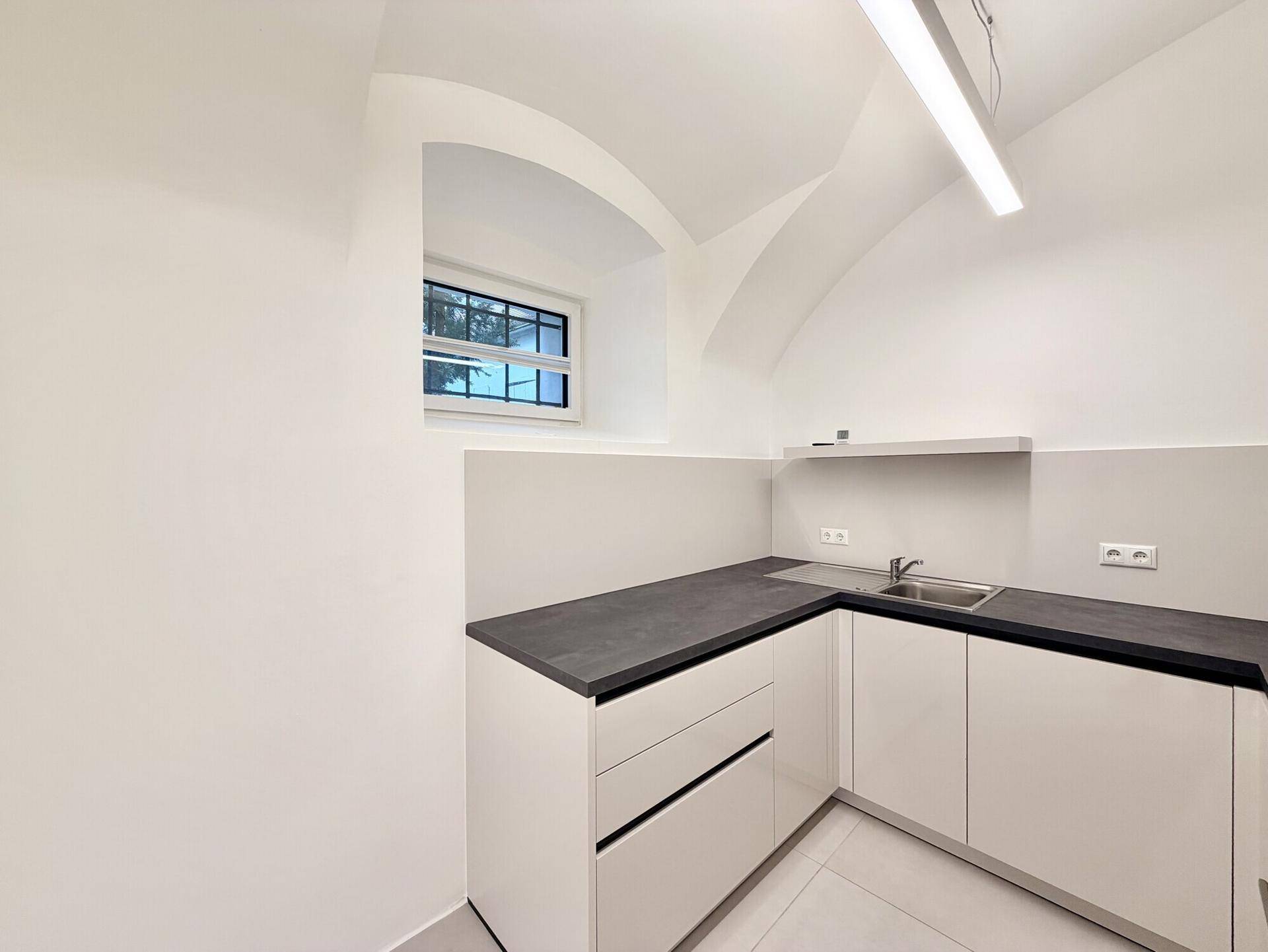Funktionale Küchenzeile mit Spülbecken, Stauraum und einem kleinen Fenster für Tageslicht.