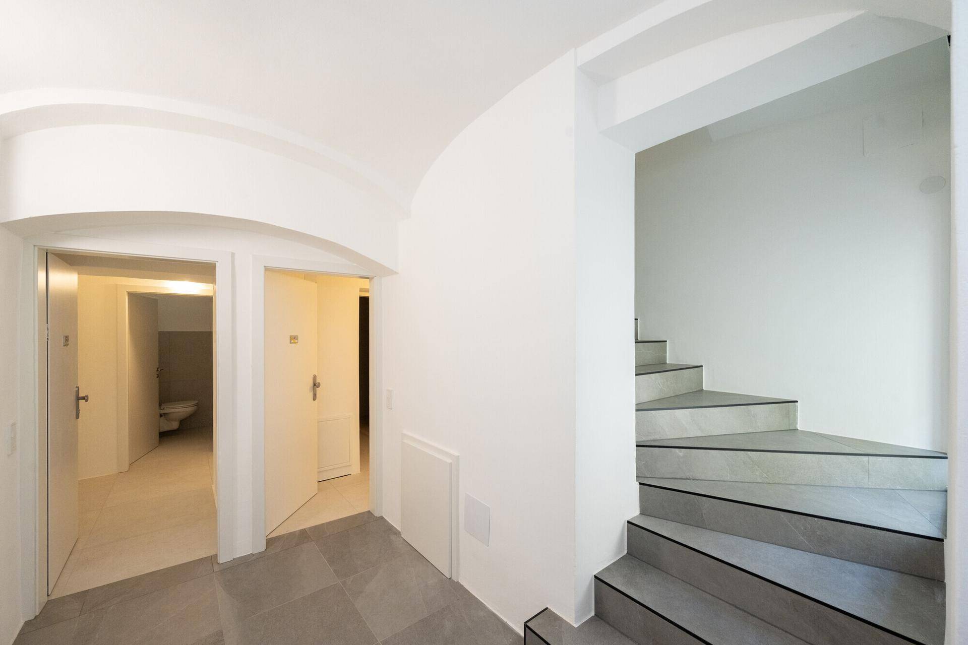 Heller Flur mit Steintreppe und Zugang zu mehreren Räumen, die frisch renoviert wurden.