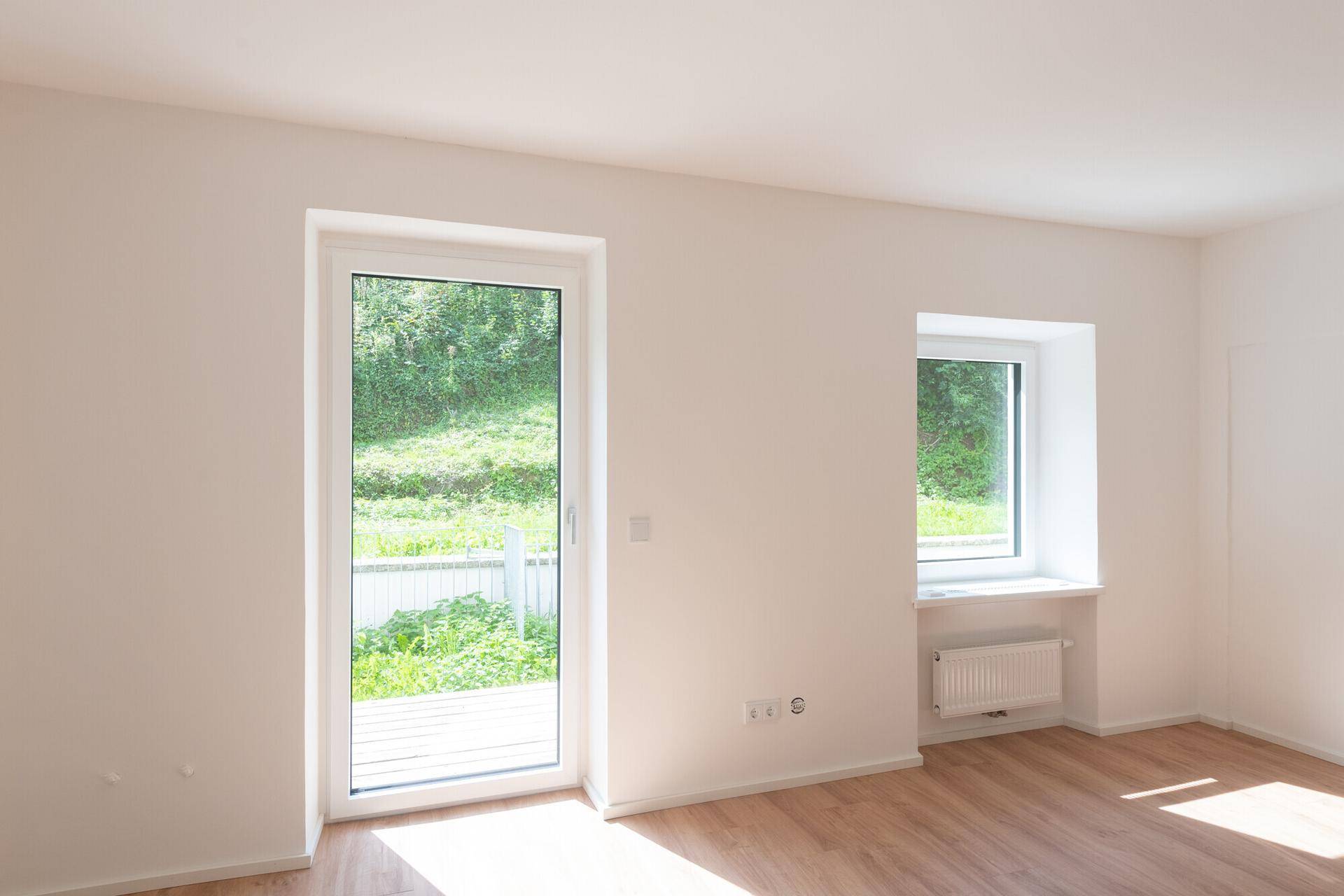Heller Wohnraum mit Zugang zur Terrasse und einem schönen Blick ins Grüne.