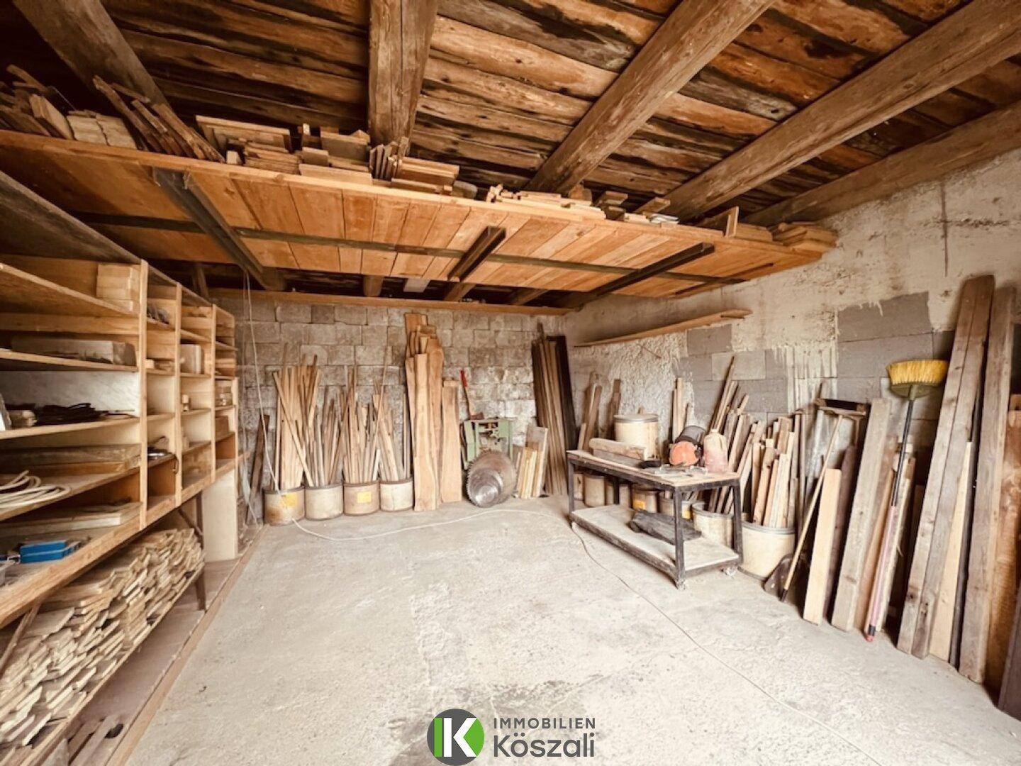 Lagerraum mit Holzregalen und Baumaterialien unter freiliegenden Holzbalken und Holzbrettern.