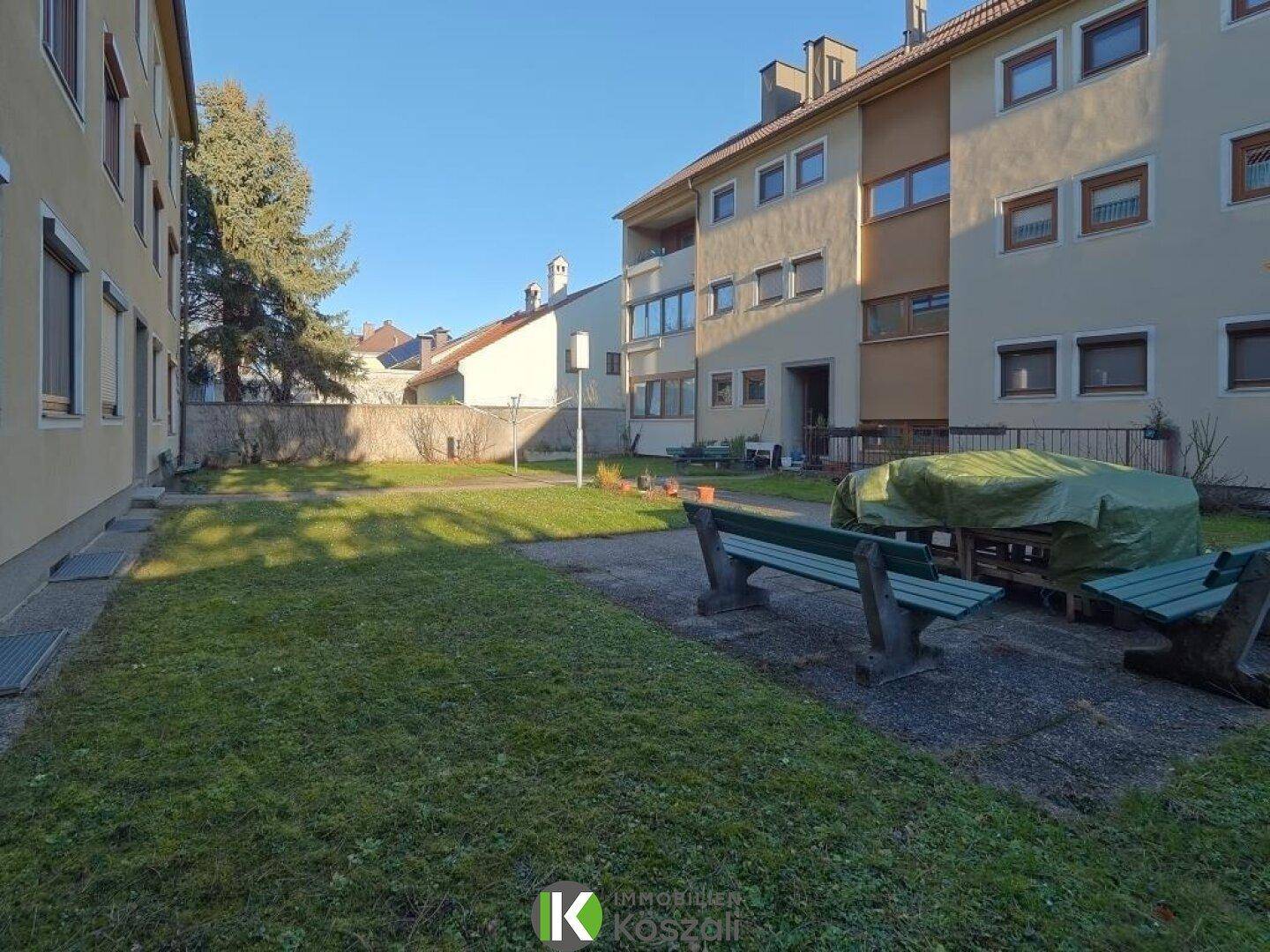 Gepflegter Gemeinschaftsgarten mit Rasenflächen und Sitzbänken, umgeben von der Wohnanlage.