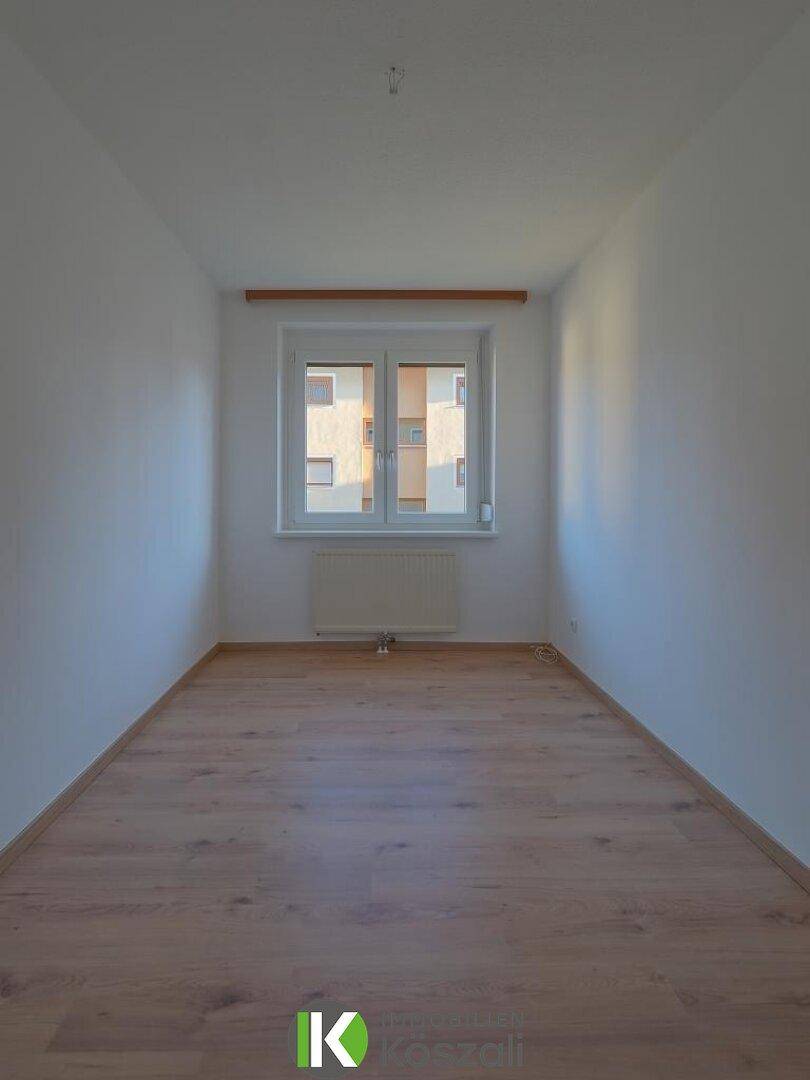 Lichtdurchflutetes, leeres Zimmer mit Holzboden und Fenster, bereit für individuelle Gestaltung.
