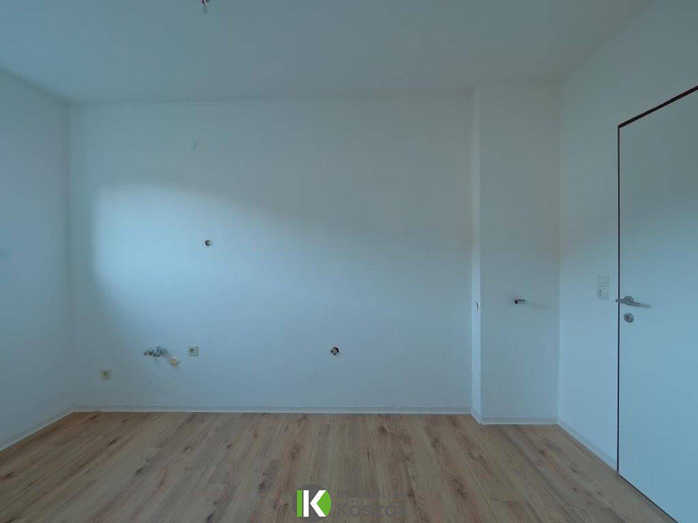 Leeres Zimmer mit hellen Wänden und Holzboden, bietet Platz für individuelle Einrichtungsideen.