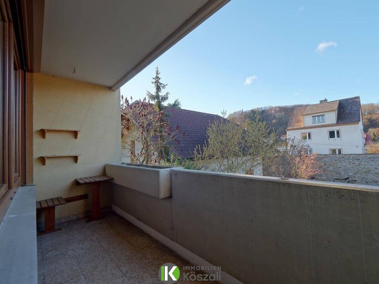 Gemütlicher Balkon mit Blick auf die Umgebung und kleine Ablageflächen aus Holz.