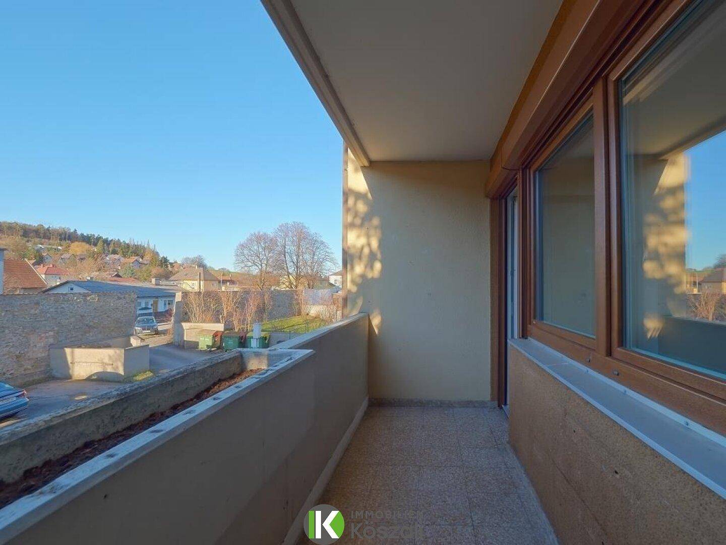 Heller Balkon mit Blick auf die Umgebung und Zugang zum Innenbereich durch eine große Fenstertür.