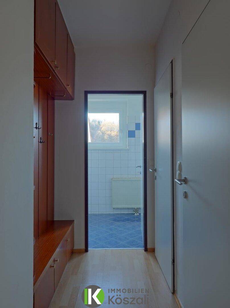 Eingangsbereich mit praktischen Einbauschränken und Garderobe aus Holz, führt zum Badezimmer.
