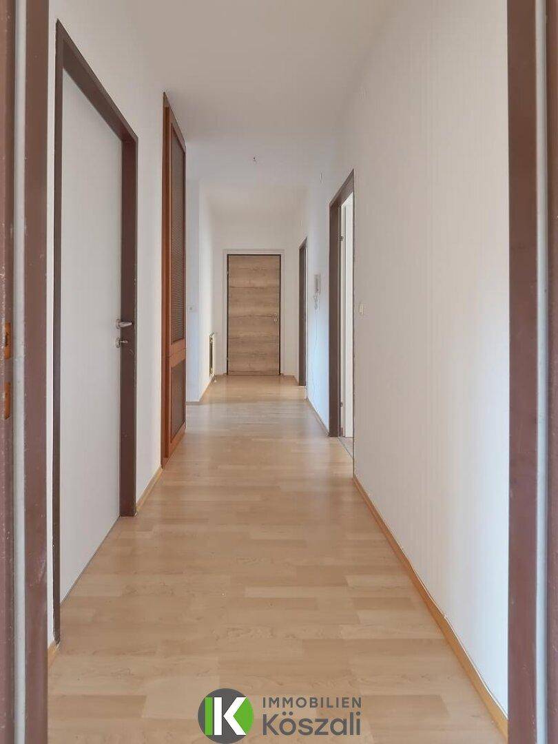 Langer, heller Flur mit Holzboden und mehreren Türen, der die verschiedenen Wohnbereiche verbindet.