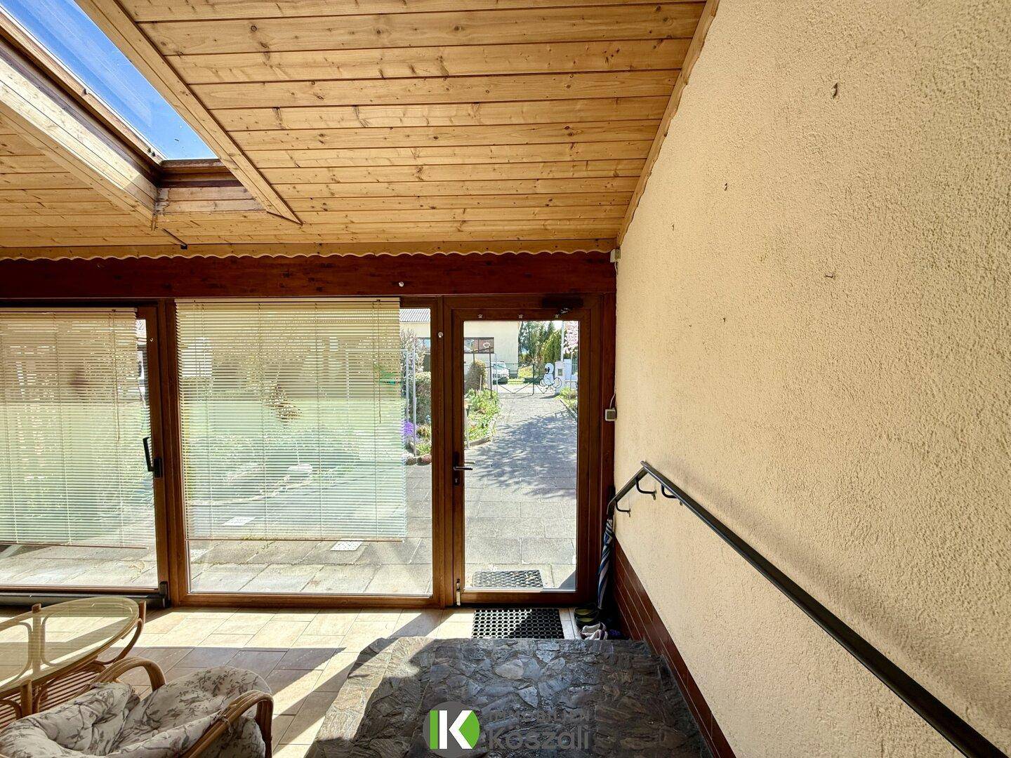 Eingangsbereich des Wintergartens mit Glastür zur Straße, Treppe und praktischem Handlauf.