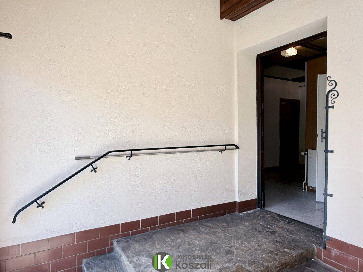 Eingangsbereich mit Treppe und stabilem Handlauf, der zum Innenbereich des Hauses führt.