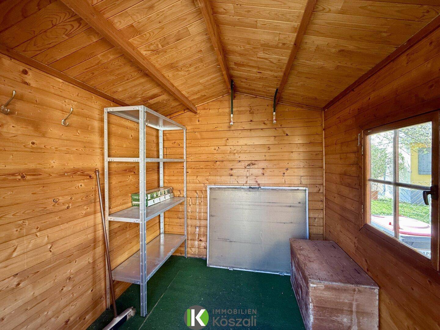 Geräumiger Holzschuppen mit Regalen und Fenster, ideal zur Aufbewahrung von Gartengeräten.
