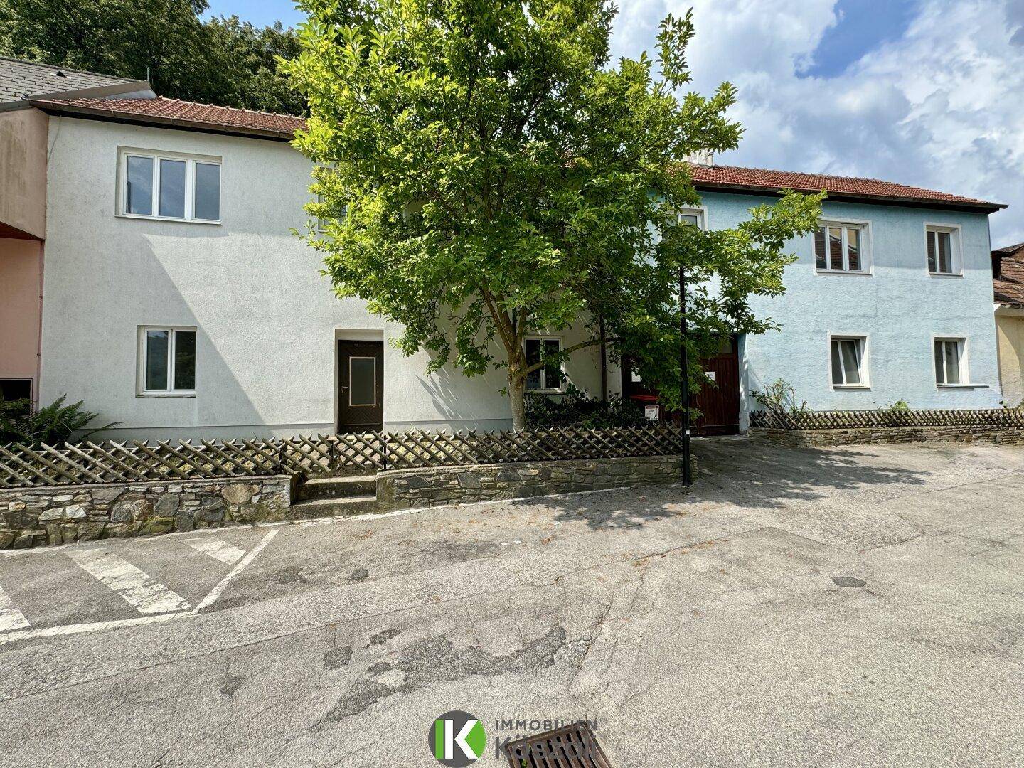 Ansicht der Gebäudefassade mit einem Baum davor und einer ruhigen Straße im Vordergrund.