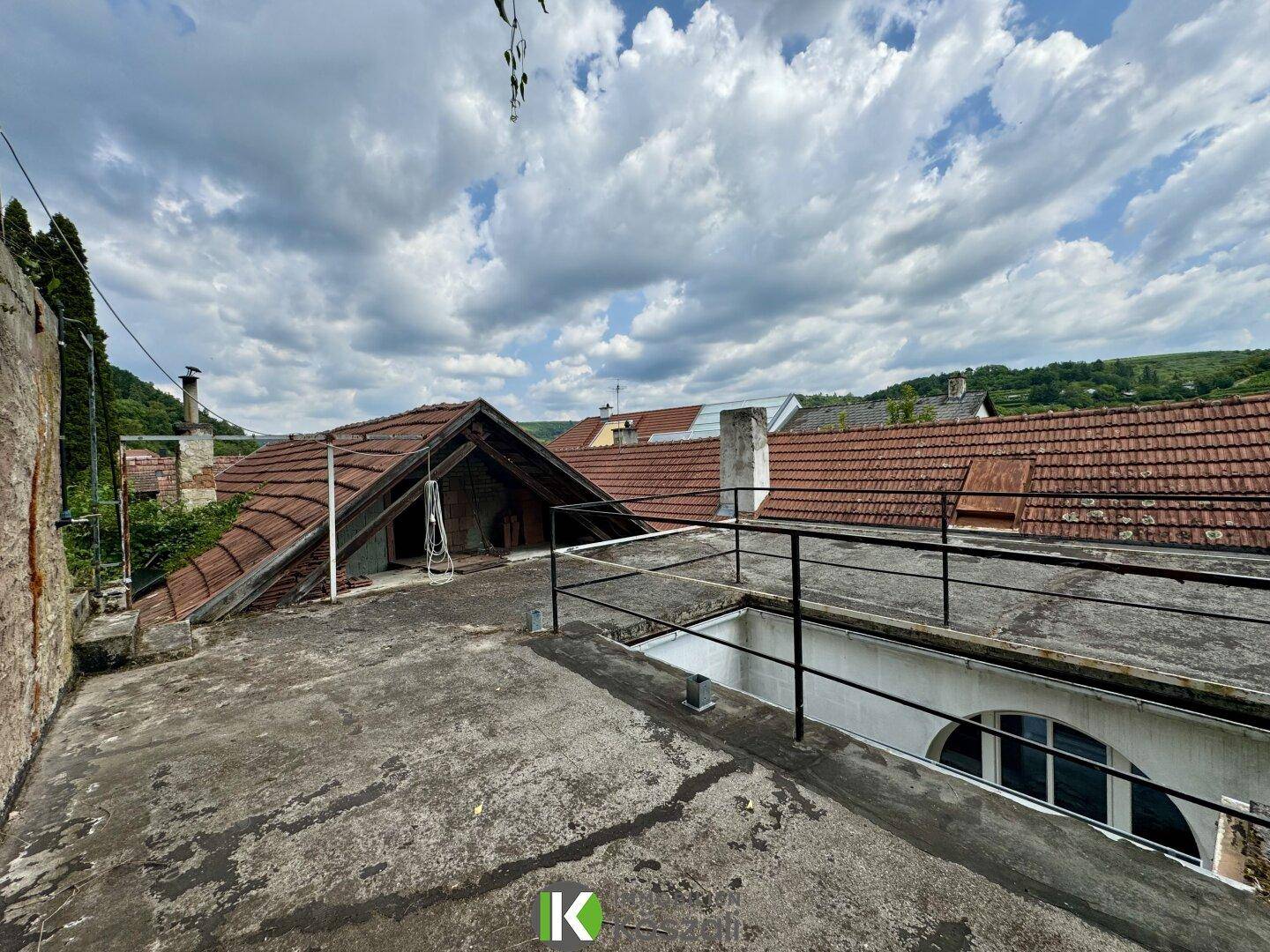 Dachterrasse mit Blick auf die umliegenden Dächer und den Himmel, benötigt Renovierung.