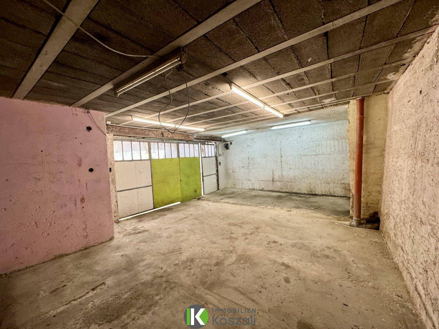 Geräumige Garage oder Lagerraum mit Betonboden und einfachen Leuchtstoffröhren.