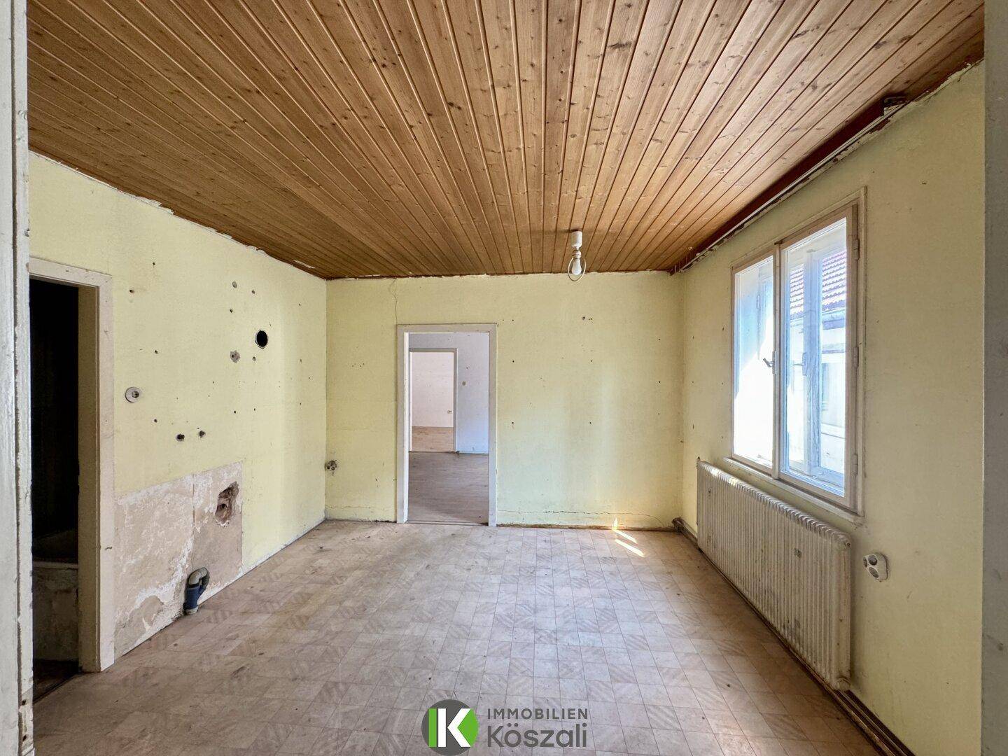 Küche in Renovierung mit Holzpaneeldecke und gemustertem Linoleumboden, bereit für den Ausbau.