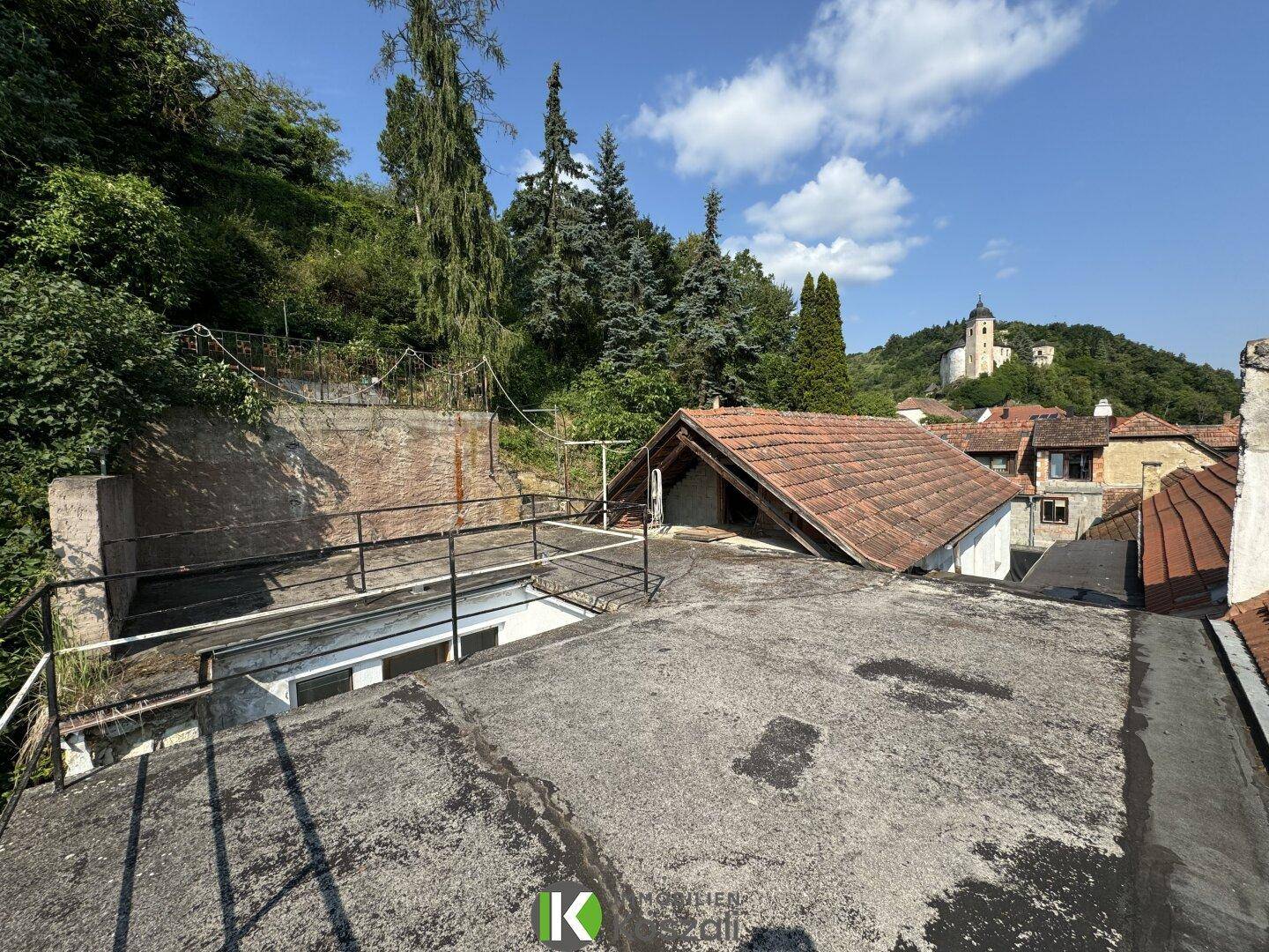 Dachterrasse mit weitem Blick über die Dächer und die hügelige Landschaft mit einer Kirche.