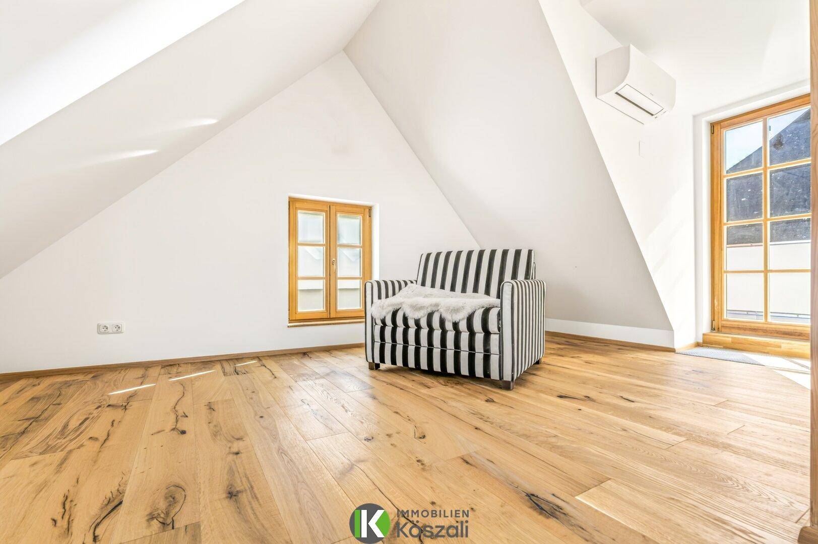 Helles Dachgeschosszimmer mit Holzboden, Dachschräge und Klimaanlage, ideal als Schlafzimmer.