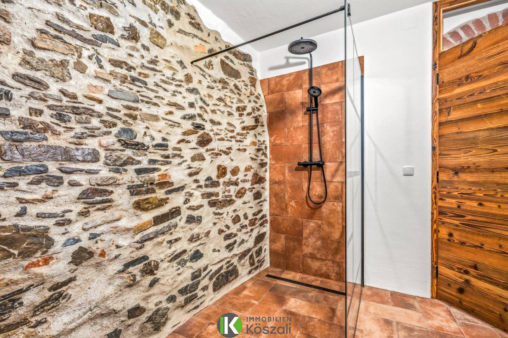 Modernes Badezimmer mit begehbarer Dusche, Regendusche und rustikalen Steinwänden.