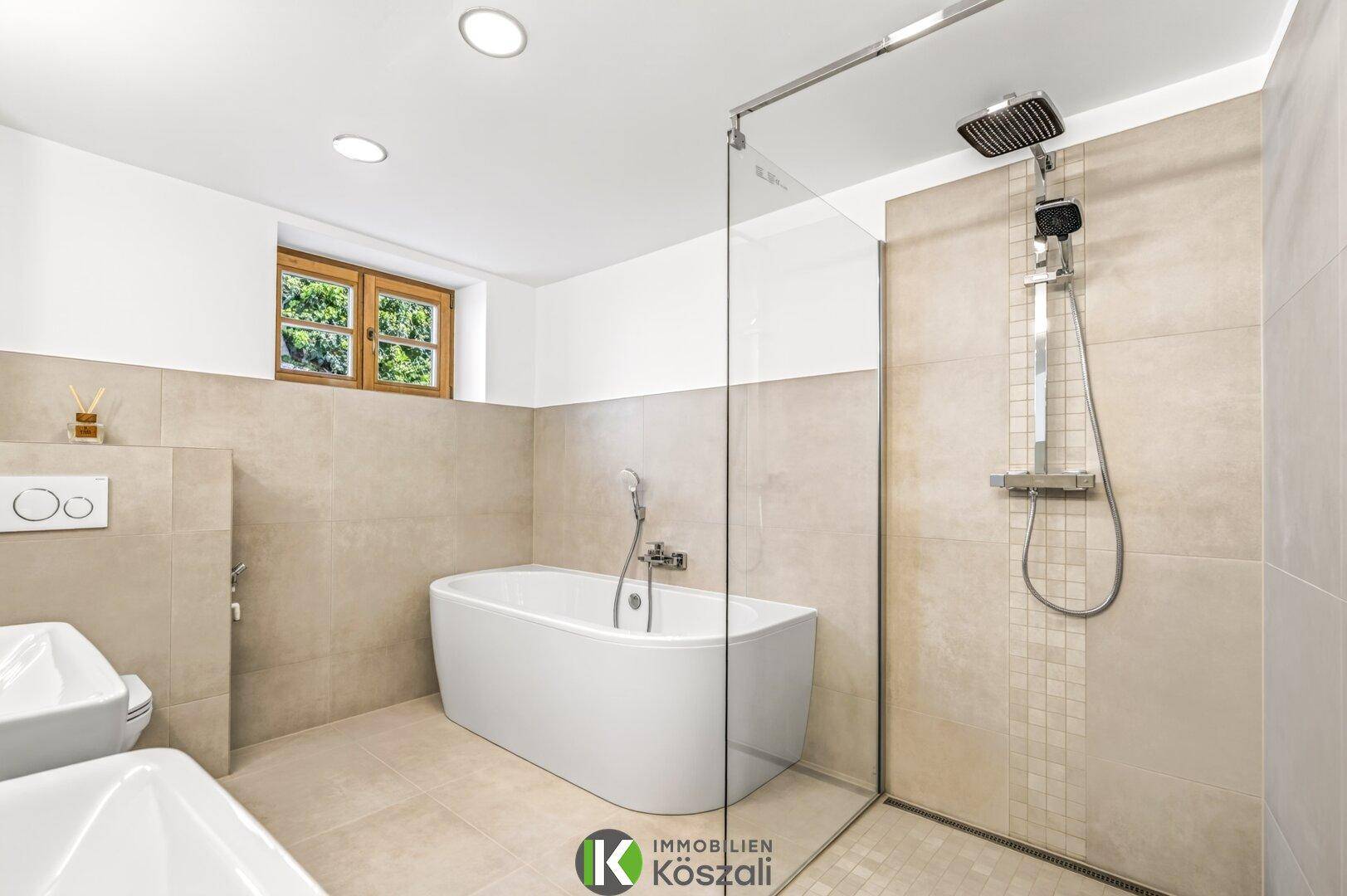 Elegantes Badezimmer mit freistehender Badewanne, begehbarer Dusche und großformatigen Fliesen.