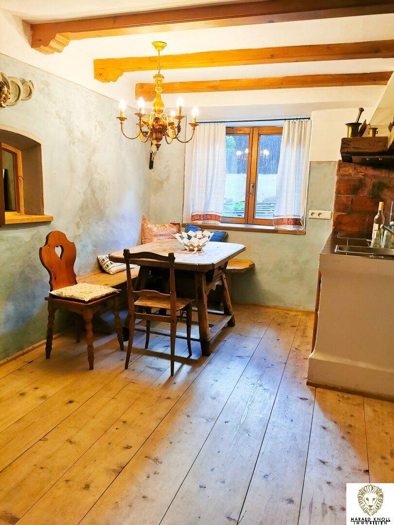 Rustikale Küche mit Holzboden, Esstisch und sichtbaren Deckenbalken in traditionellem Stil.