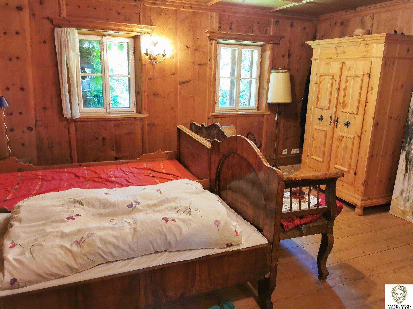 Schlafzimmer im alpenländischen Stil mit Holzvertäfelung, Holzbett und passendem Kleiderschrank.