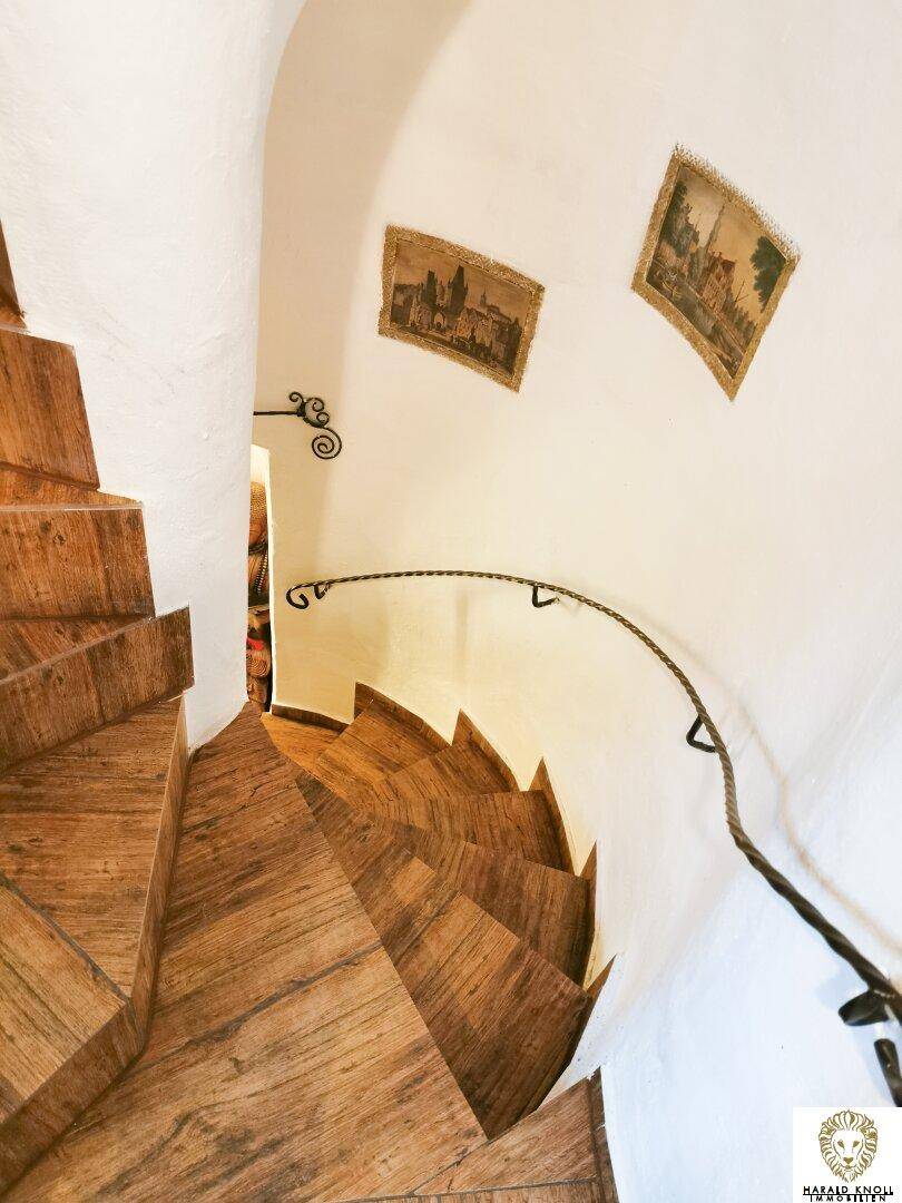 Geschwungene Holztreppe mit schmiedeeisernem Geländer, die zu den oberen Etagen führt.