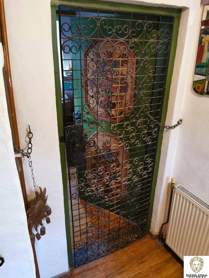 Dekoratives schmiedeeisernes Gittertor in Grün, das einen Durchgang zu einem weiteren Raum bildet.