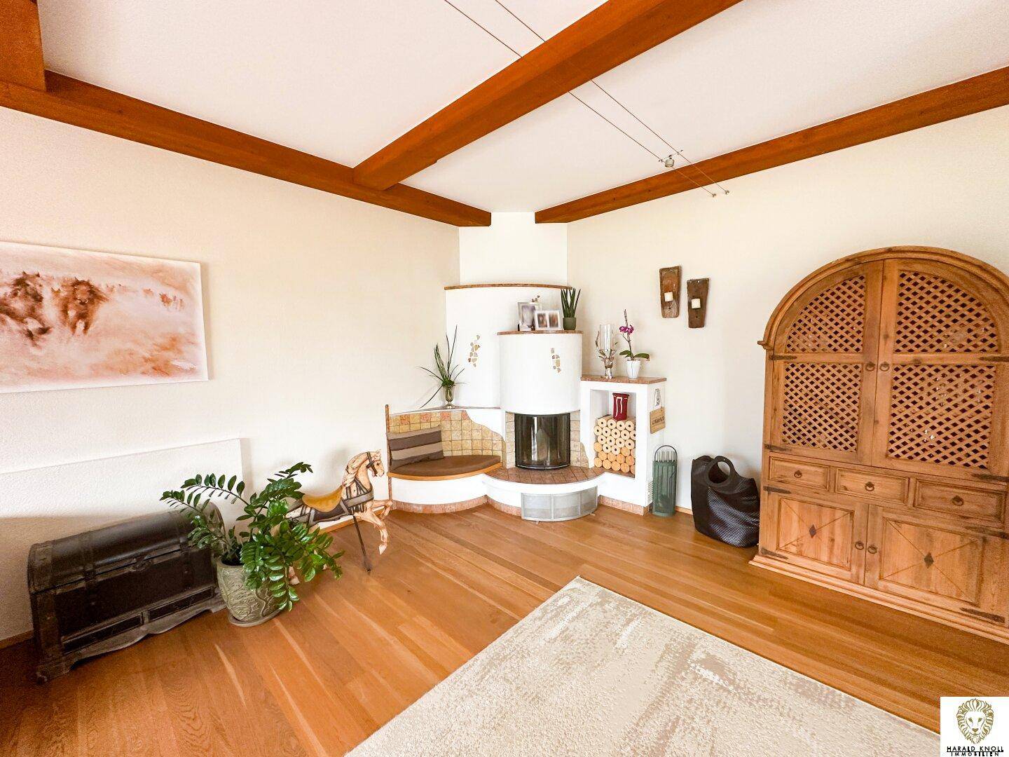 Gemütliches Wohnzimmer mit Kaminofen, Holzbalken und traditionellen Möbeln.