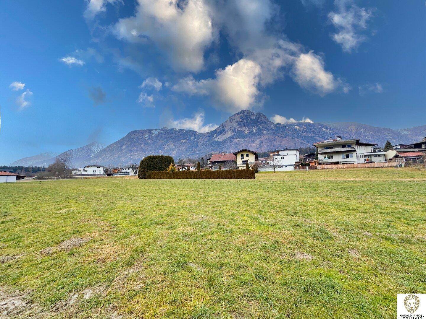 Idyllische grüne Wiese mit freiem Blick auf die imposanten Berge und charmante Häuser.