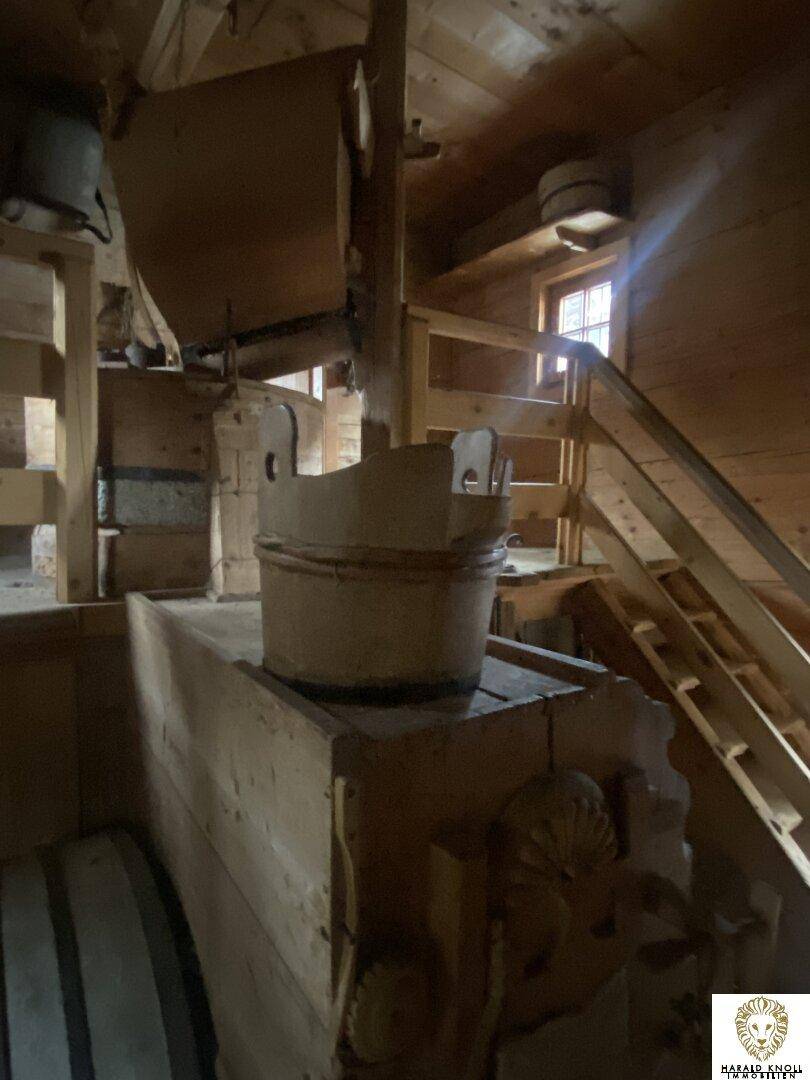 Rustikaler Innenraum aus Holz mit Treppe und traditionellen Elementen, möglicherweise ein Dachboden.