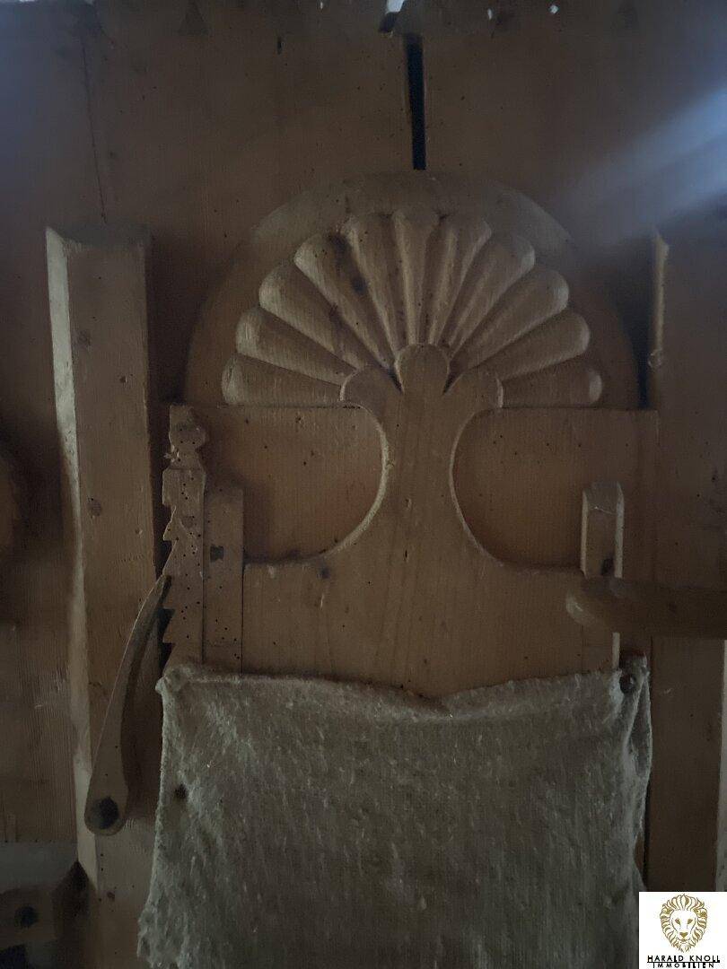 Detailaufnahme einer kunstvoll geschnitzten Holzverzierung in einem rustikalen Innenraum.