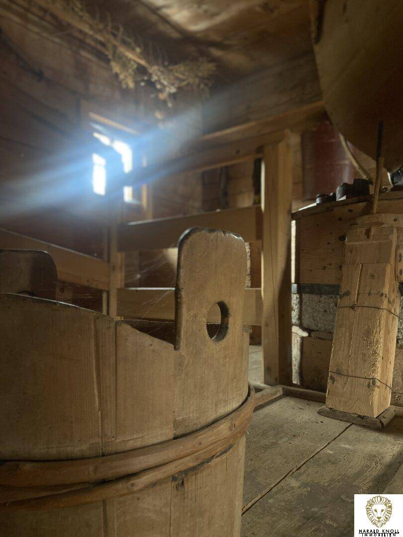 Innenraum aus Holz mit starkem Lichteinfall durch ein Fenster, rustikale Bauweise.