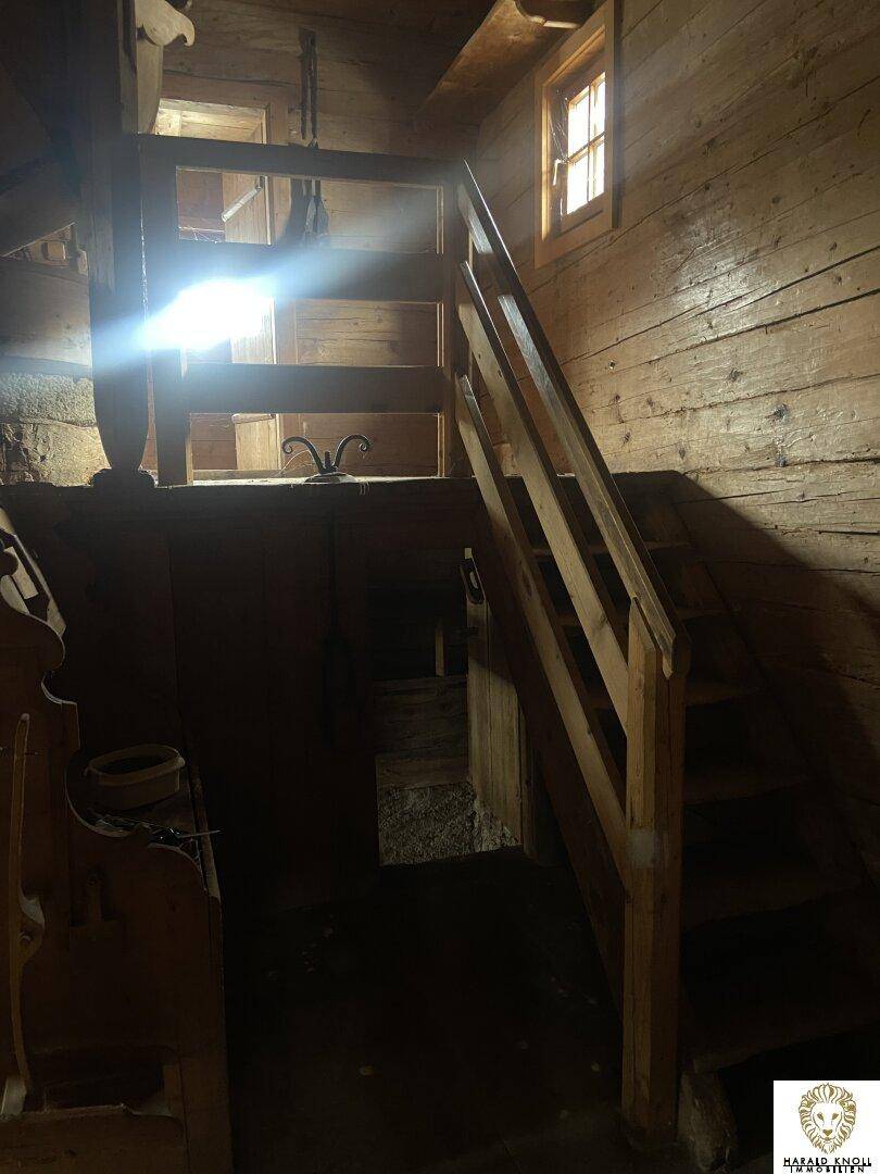 Rustikale Holztreppe in einem Innenraum mit Holzwänden und natürlichem Lichteinfall.