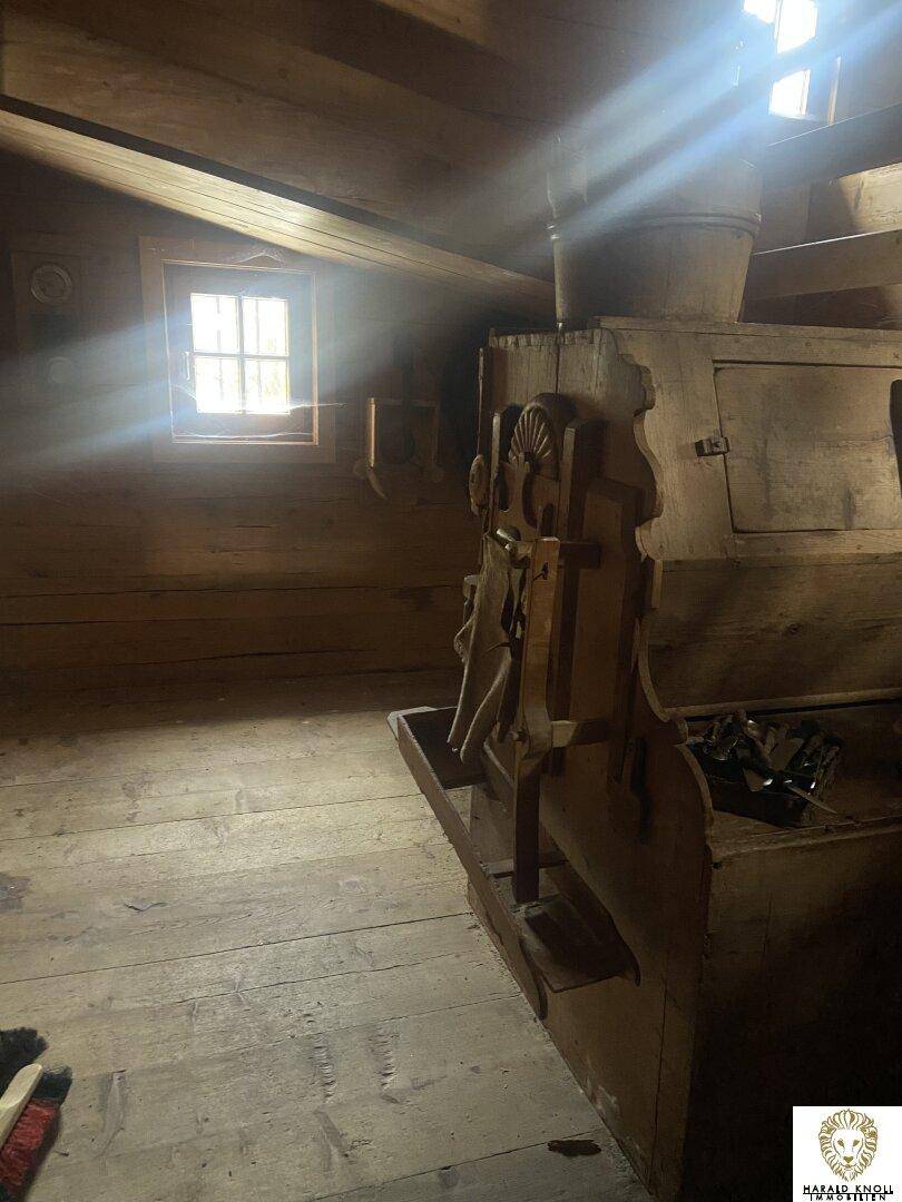 Innenraum aus Holz mit starkem Lichteinfall durch ein Fenster, rustikale Bauweise.
