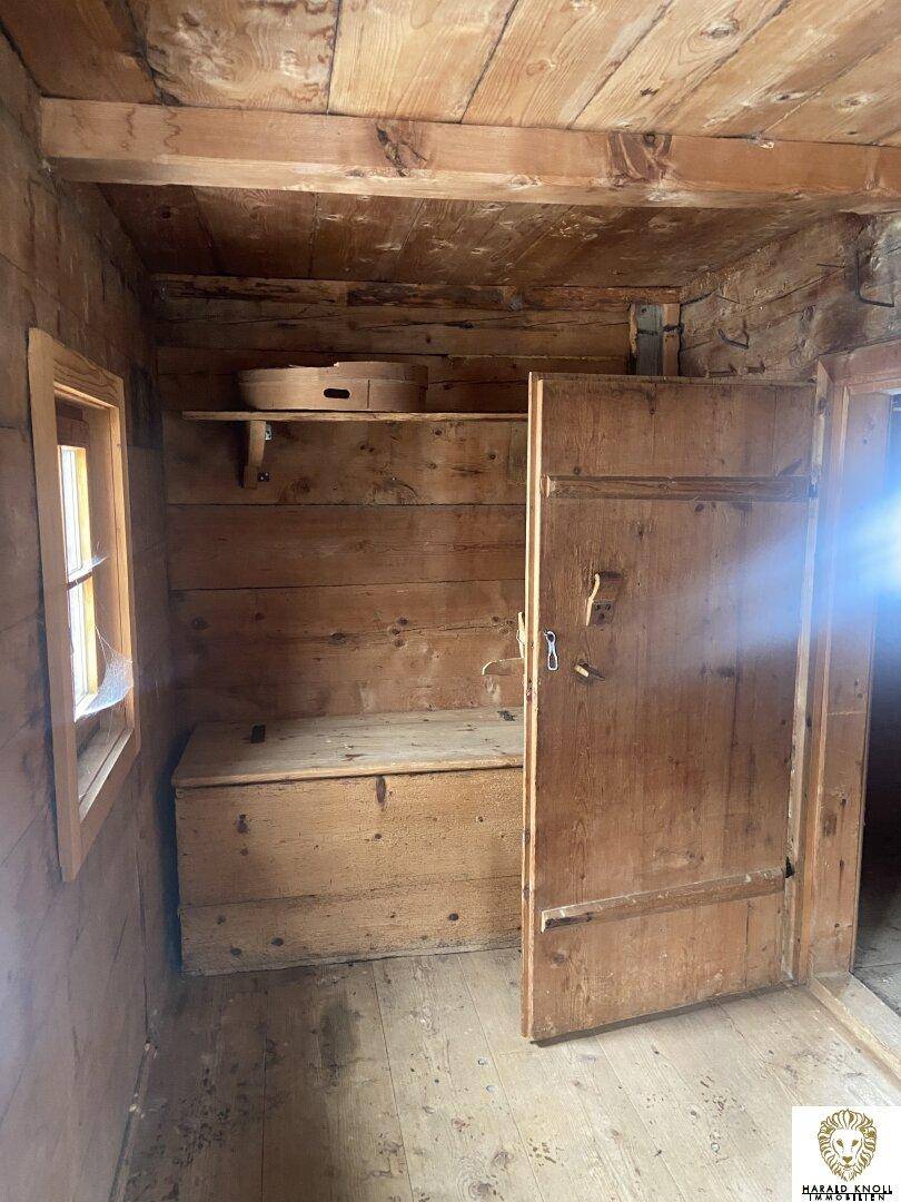 Rustikaler Raum mit Holzwänden, Holzboden und einem kleinen Fenster, ideal als Abstellraum oder kleine Kammer.