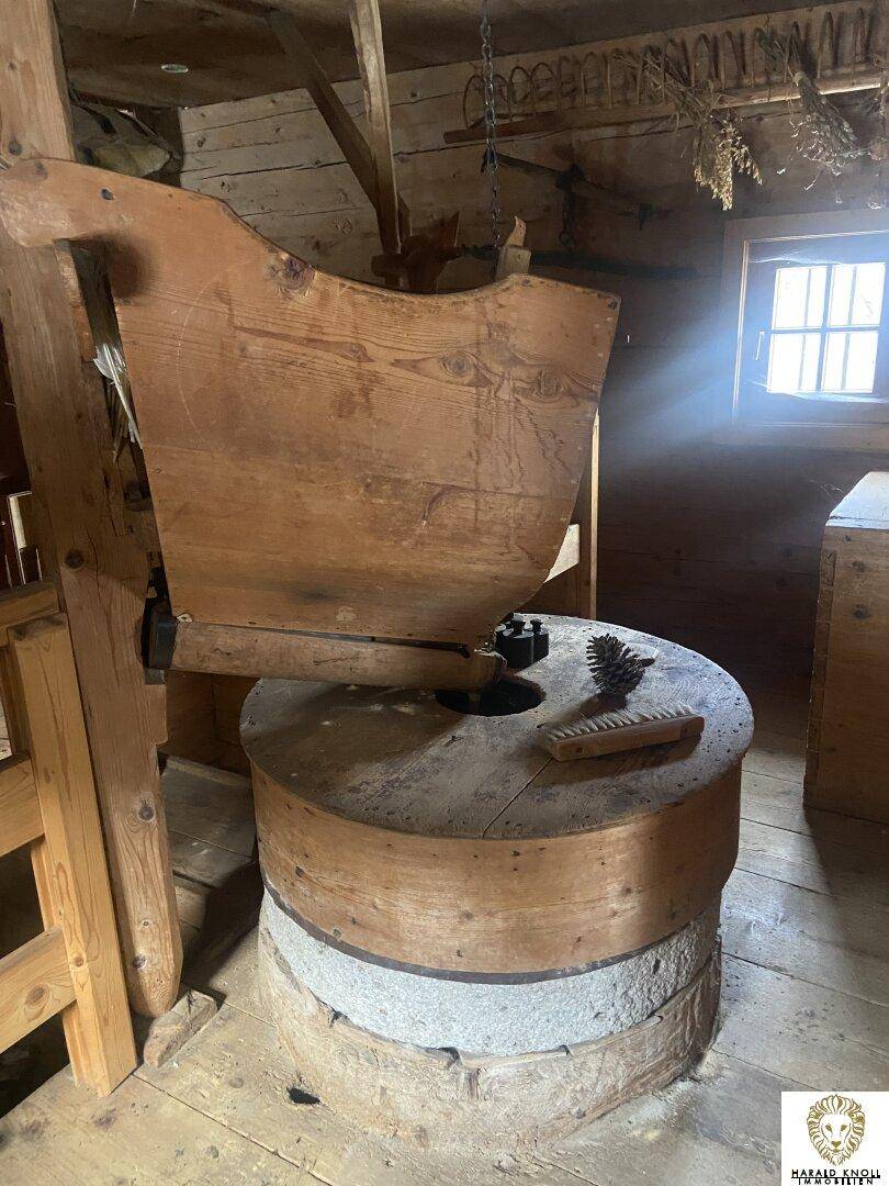 Historische Mühle oder Werkstatt mit alter Holz- und Steinkonstruktion und rustikalem Ambiente, beleuchtet durch ein kleines Fenster.