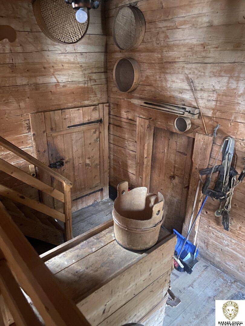 Rustikaler Flur mit Holztreppe, Holzwänden und traditionellen Gegenständen, die eine historische Atmosphäre schaffen.