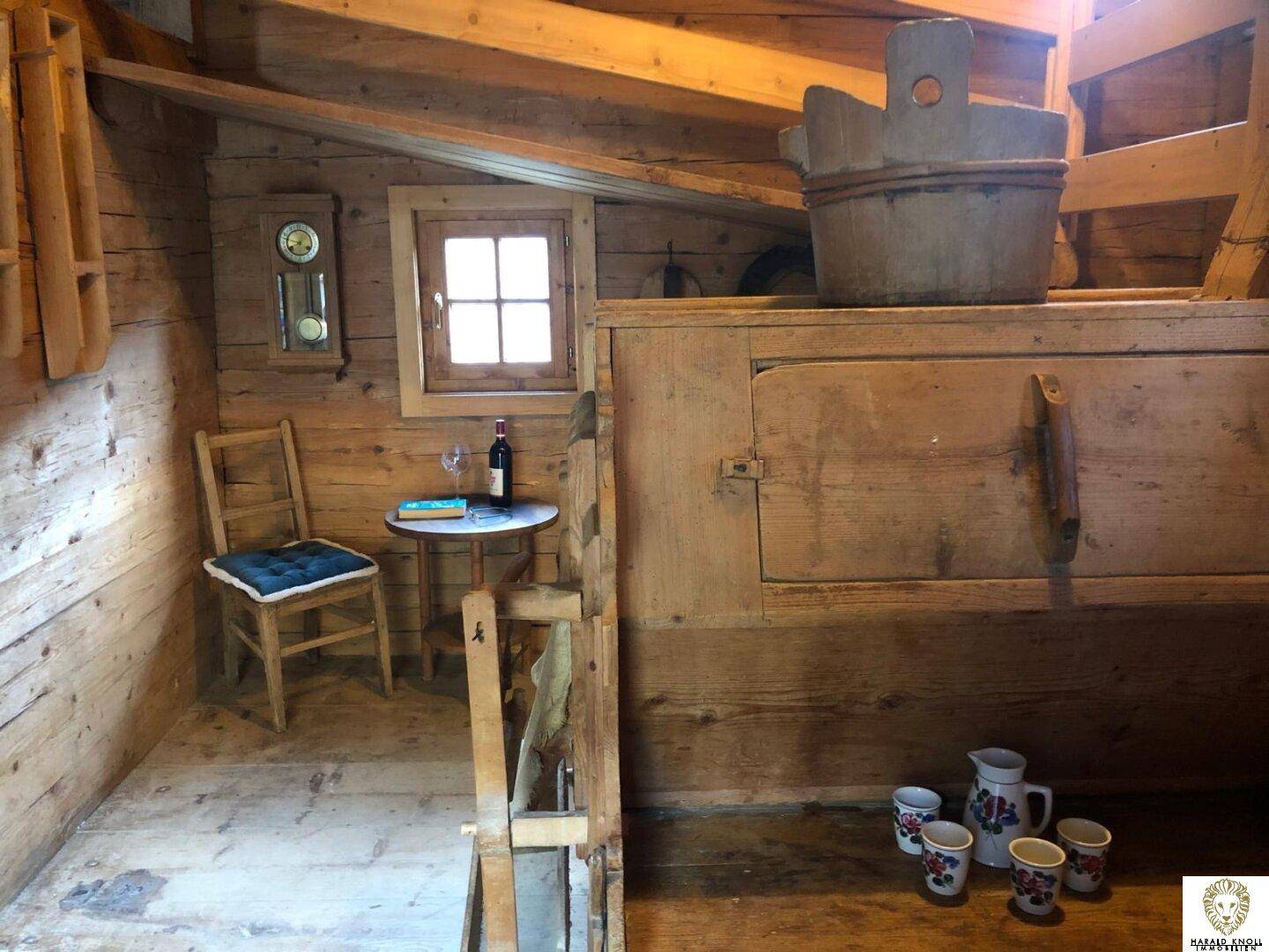 Rustikaler Wohnbereich mit Holzboden, traditionellen Möbeln und Blick aus dem Fenster.