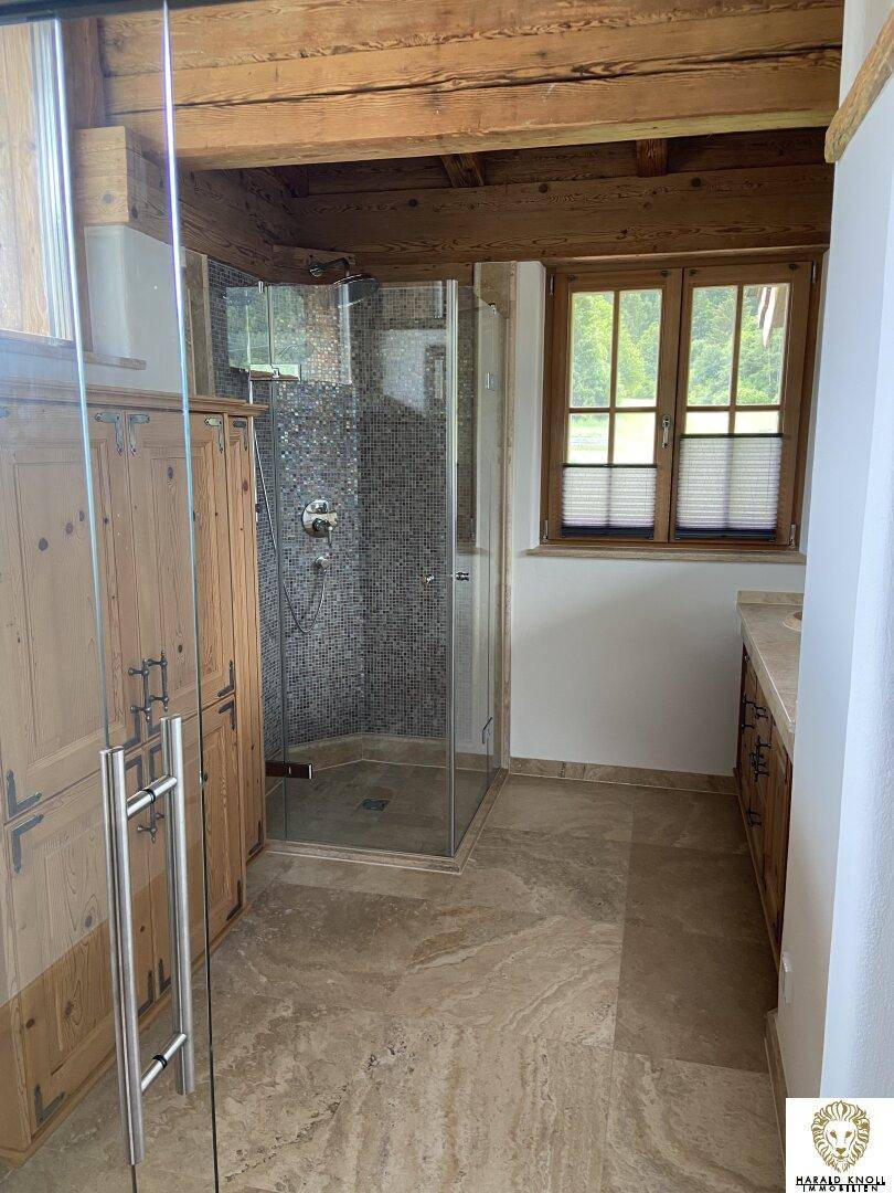 Modernes Badezimmer mit begehbarer Dusche, Holzmöbeln und Fenster.