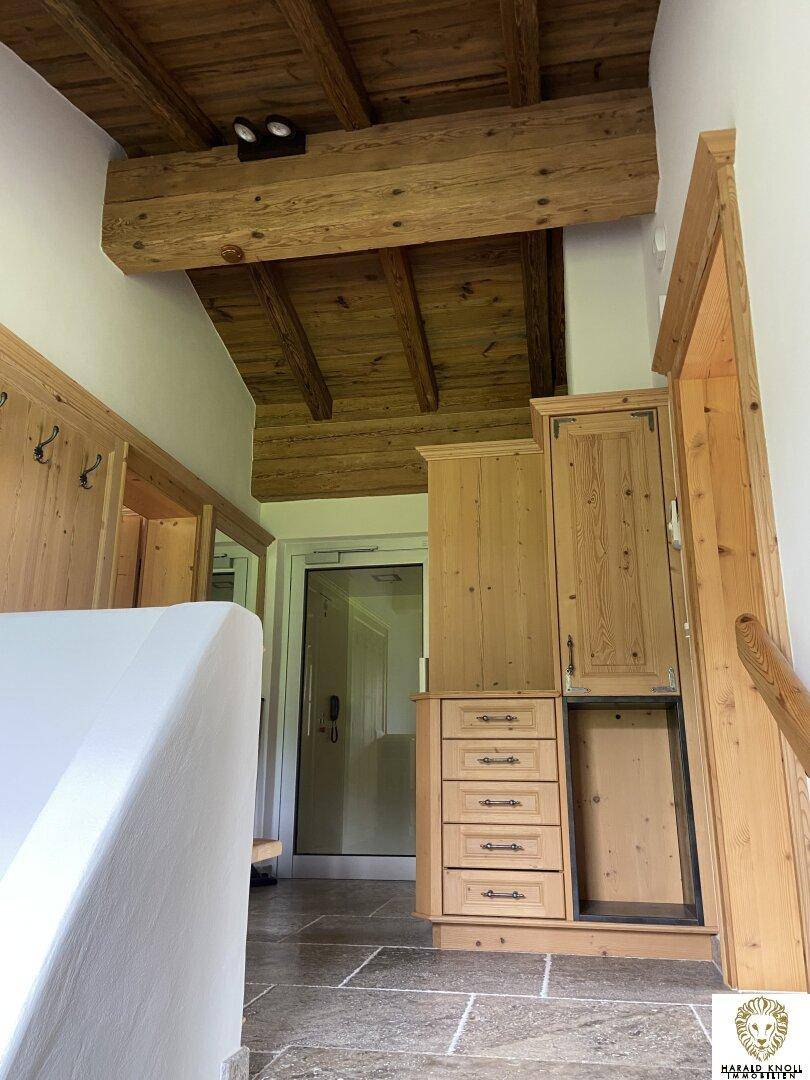 Geräumiger Flur mit Holzeinbauschränken, Steinfliesen und Zugang zum Aufzug.